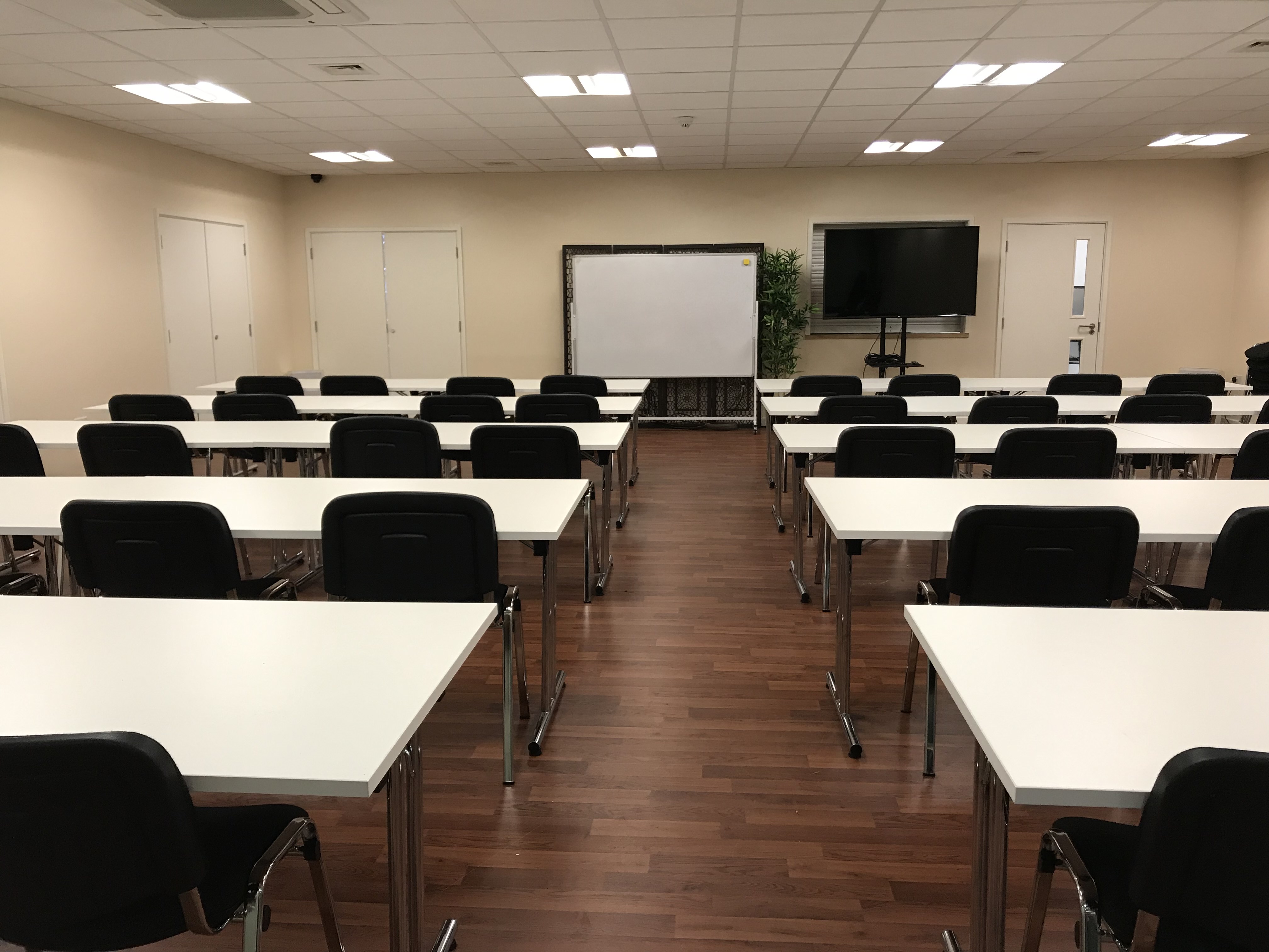 Meeting room setup for training workshop in Whitechapel, London with whiteboard and screen.