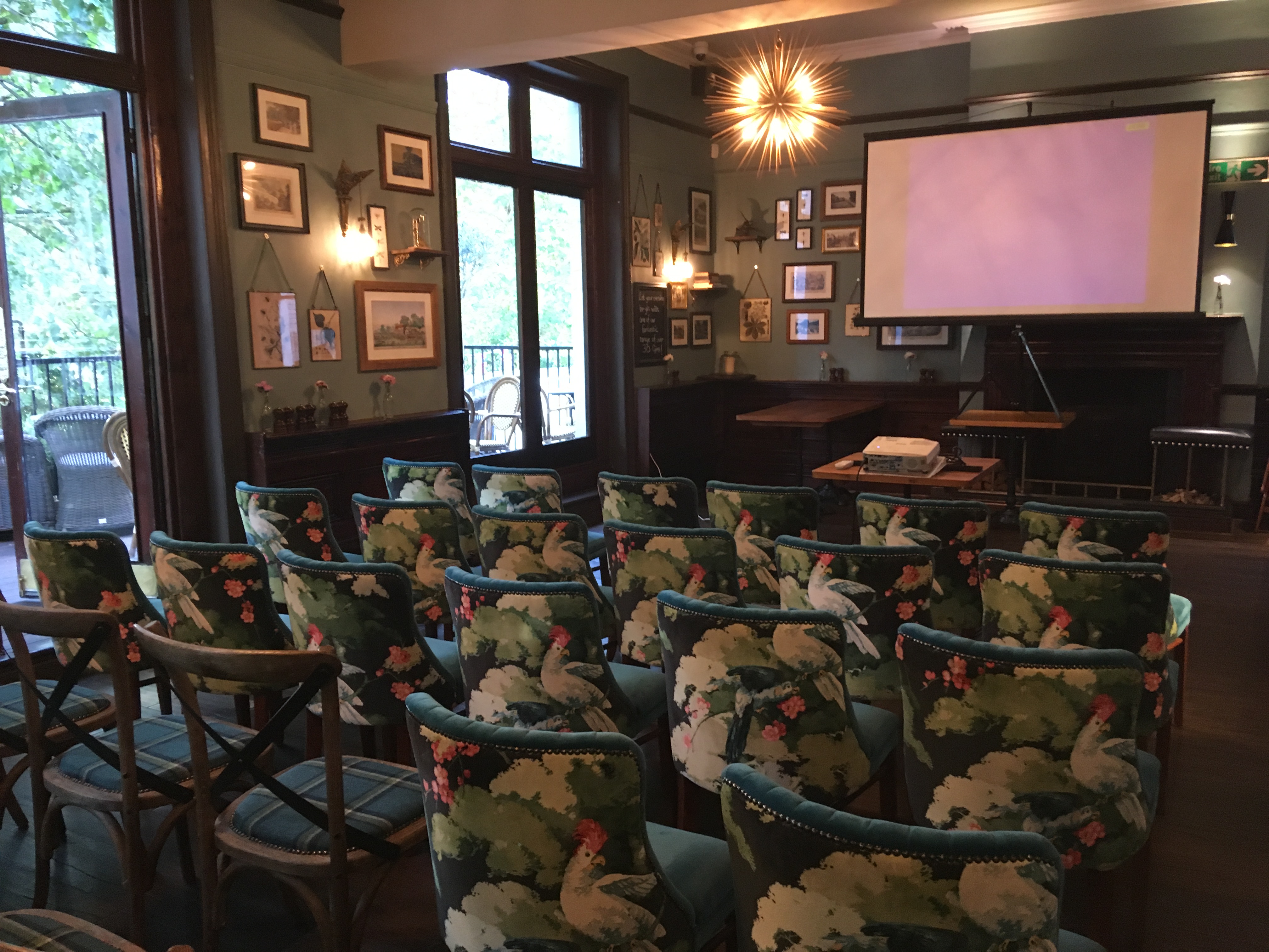 Cozy Garden Room meeting space with floral chairs for presentations and workshops.