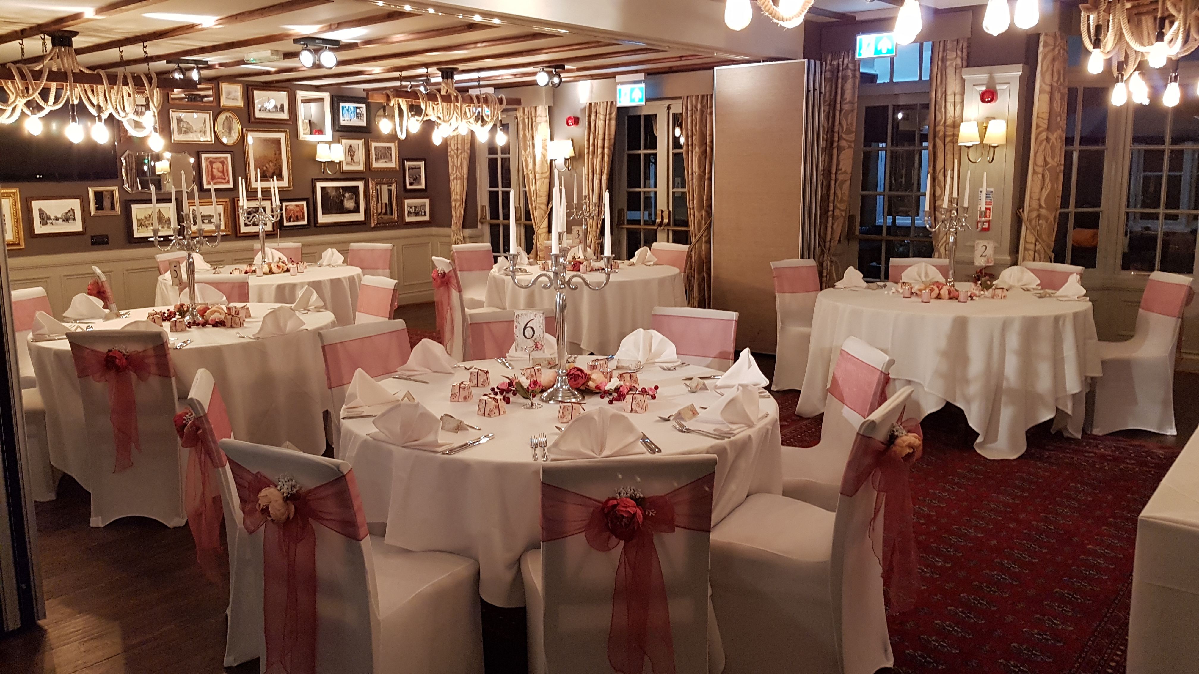 Elegant wedding venue with round tables, soft pink accents, and warm lighting.