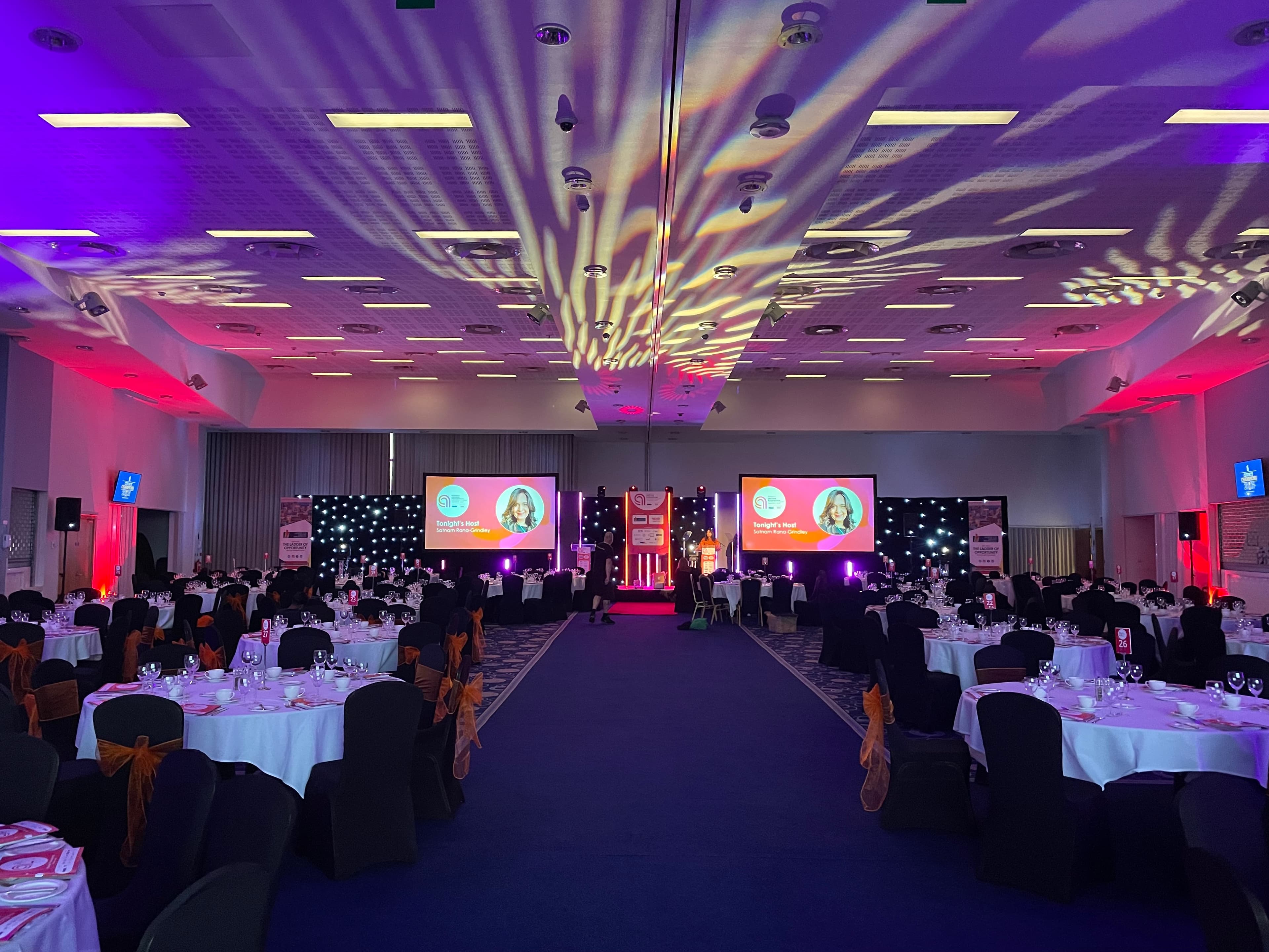 Gala dinner setup at Praba Banqueting Suite with theatrical lighting for corporate event venue.