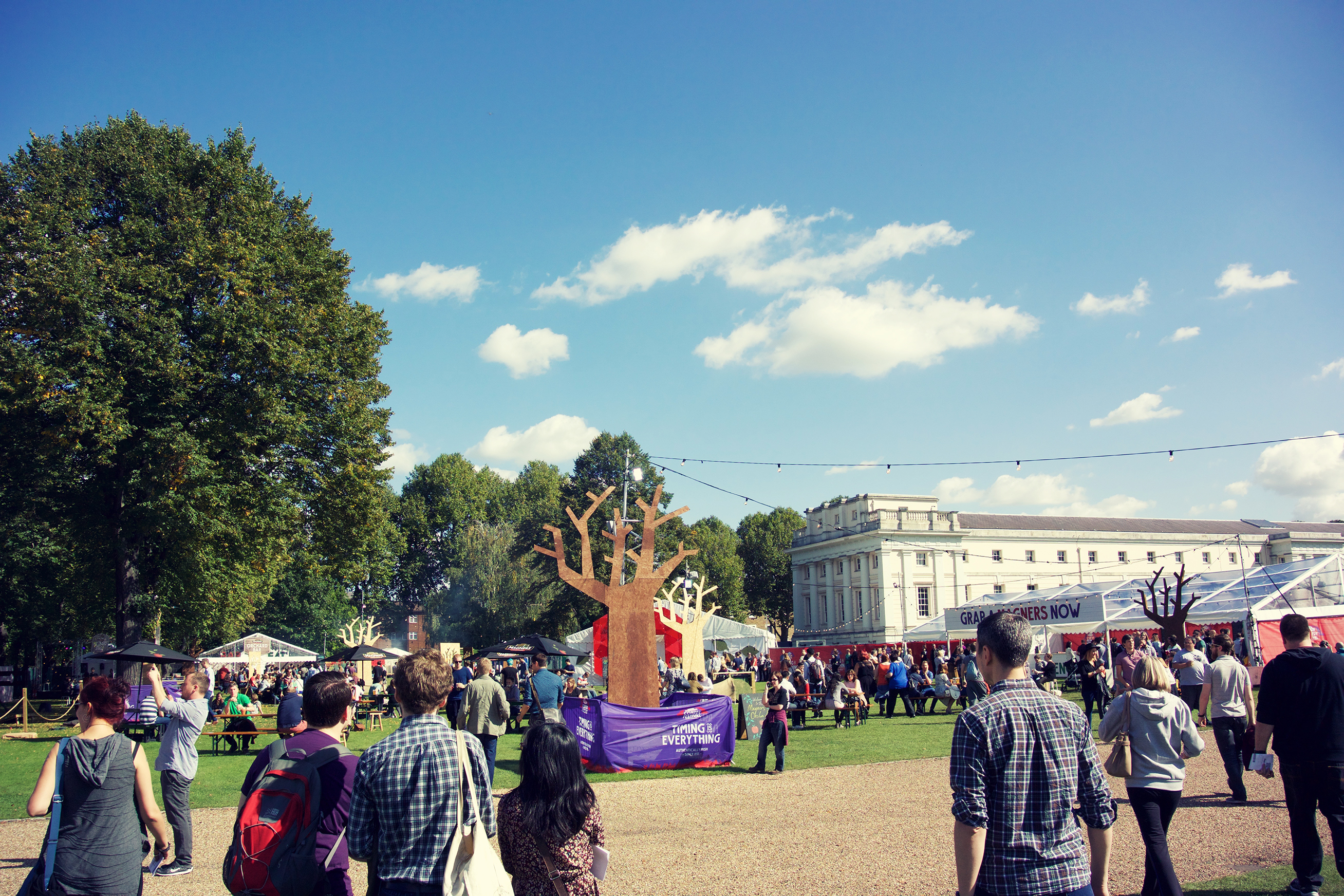 Vibrant outdoor event at South Lawns, The Queen's House with tents and tree installation.