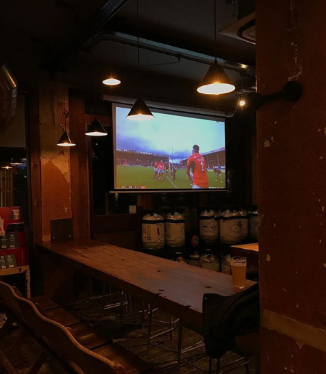 Cozy Temple Brewhouse venue with large screen for sports watch parties and gatherings.