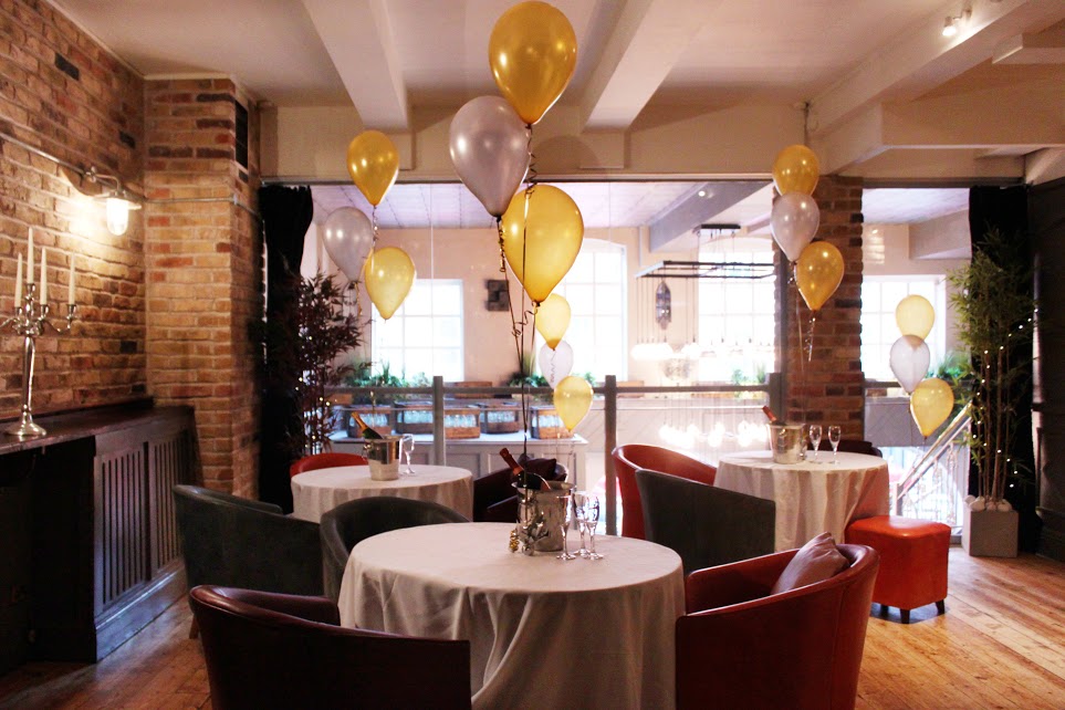 Elegant event space with white tables and colorful balloons for gatherings or celebrations.