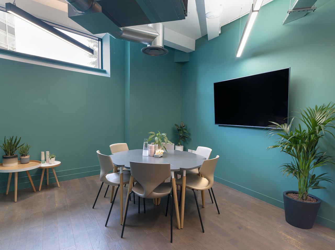 Modern meeting room LG.02 with teal walls, circular table for collaboration events.