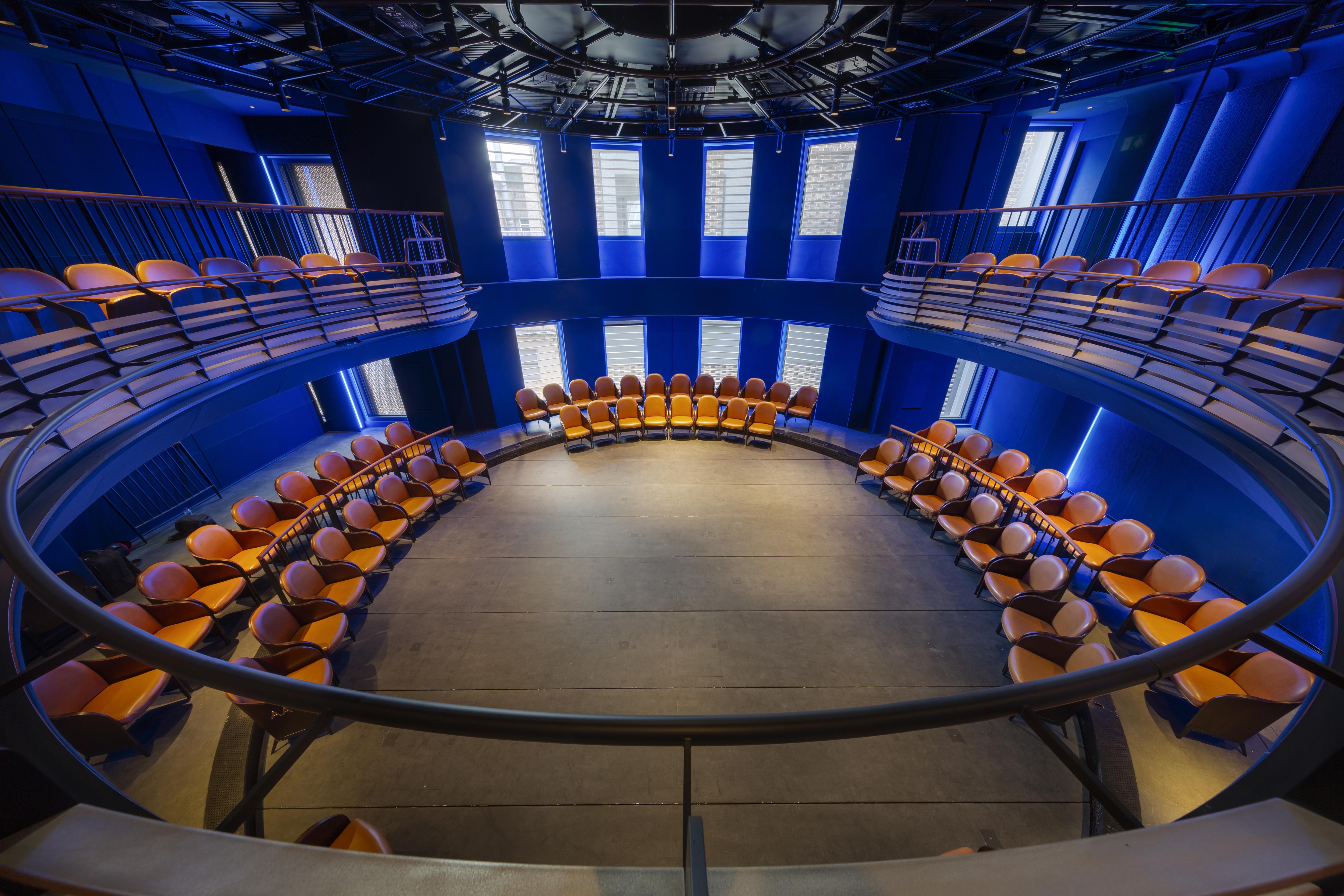 Modern auditorium with circular seating and vibrant blue lighting for engaging events.