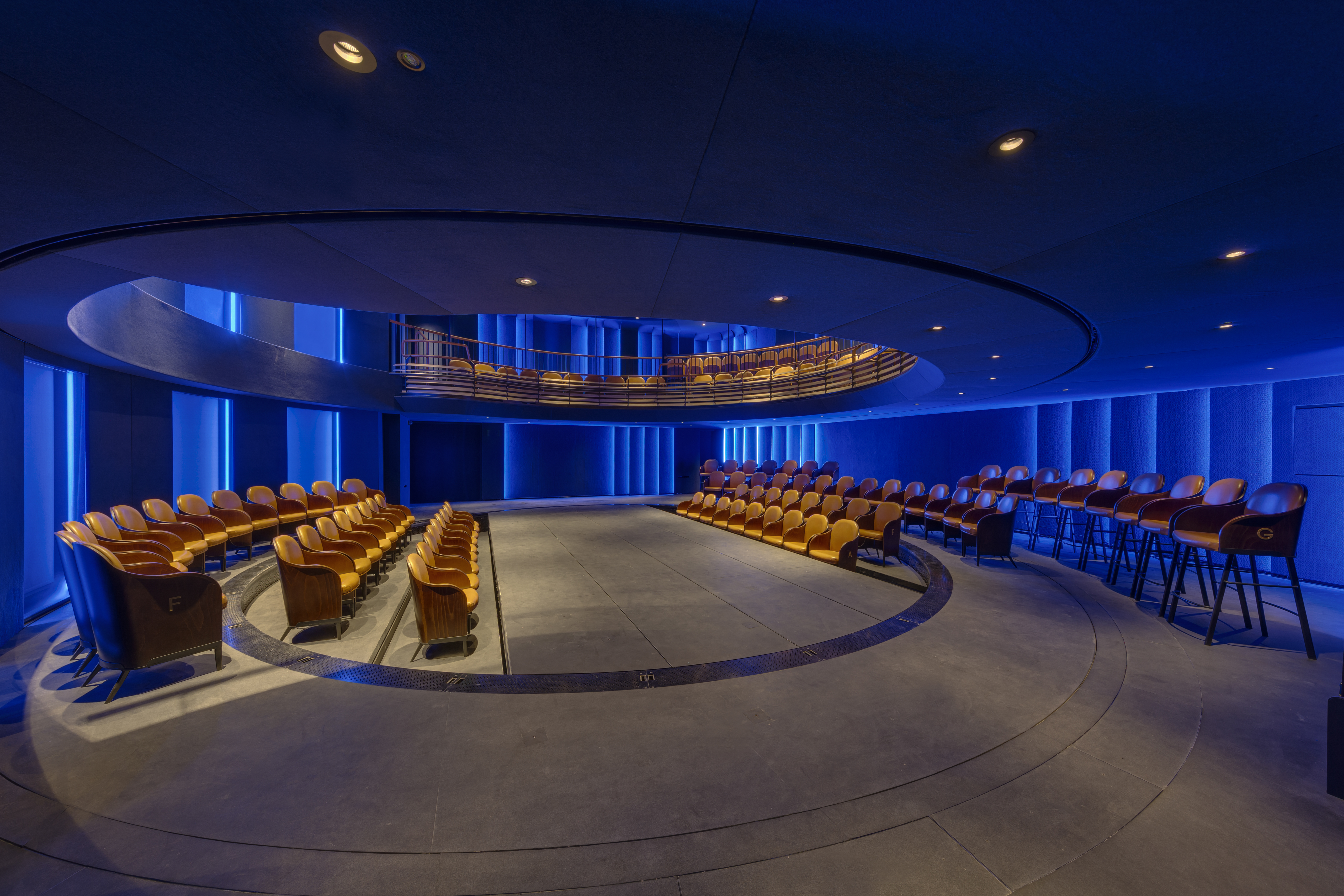 Modern auditorium with tiered seating and blue lighting for corporate events.