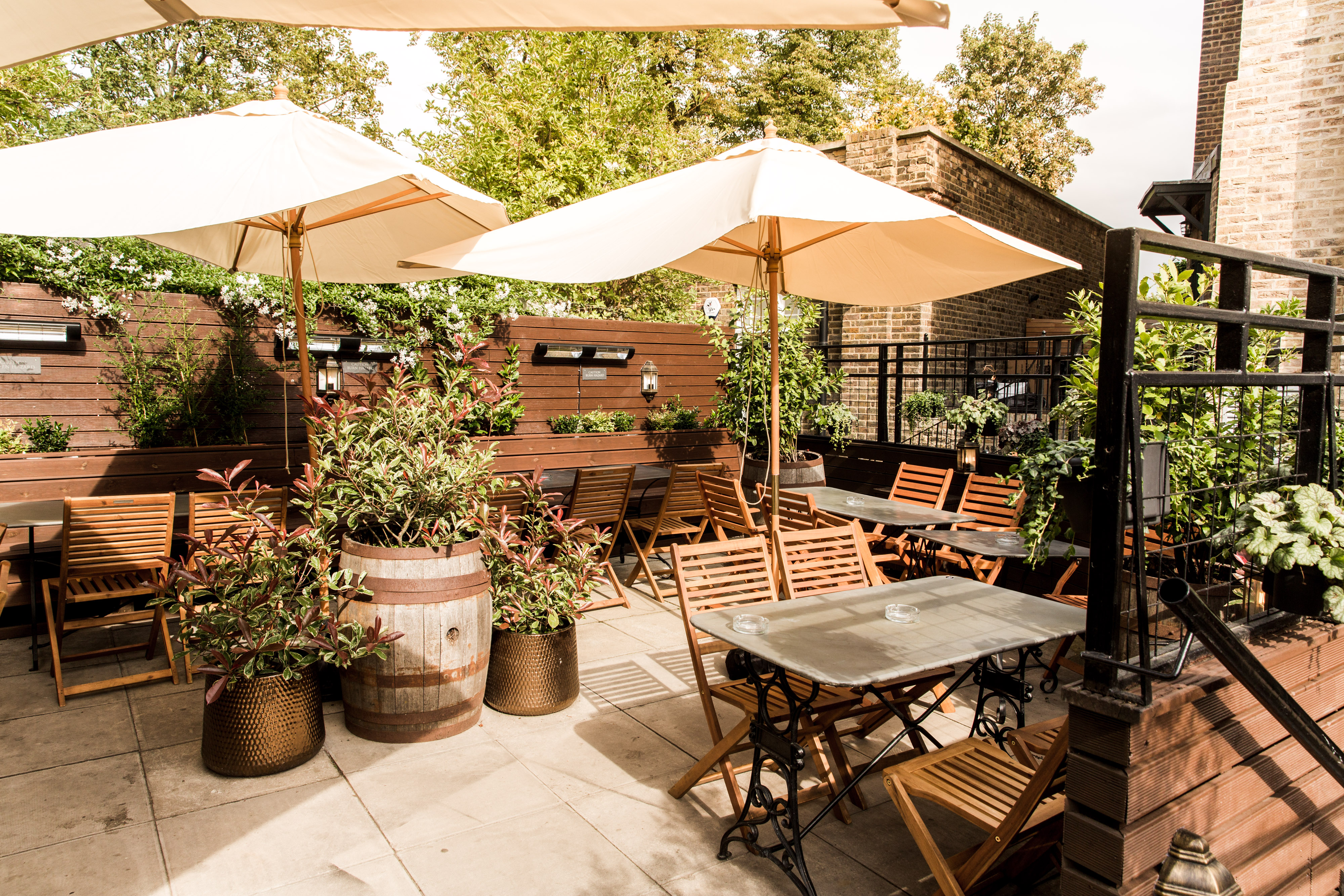 Charming outdoor event space with wooden furniture and lush greenery for summer gatherings.