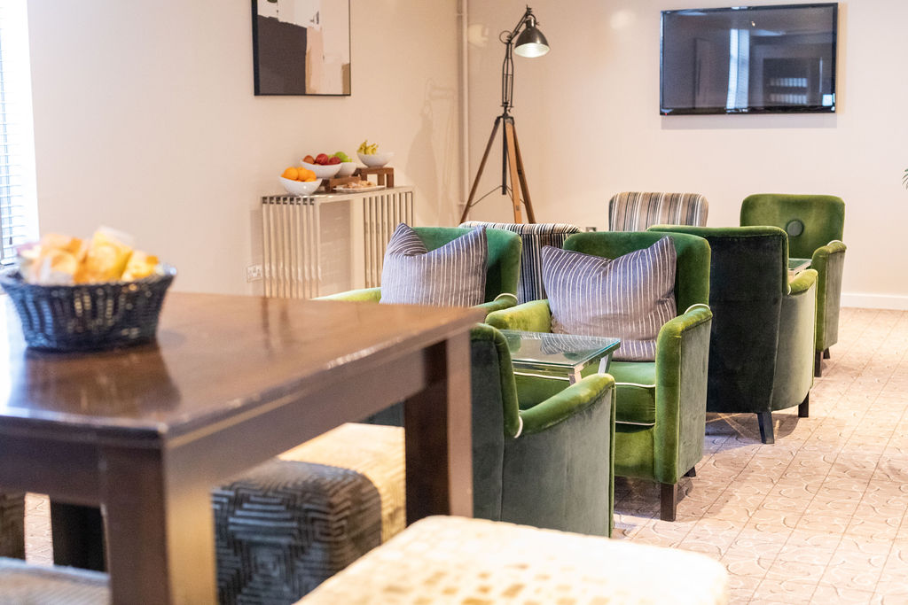 Stylish lounge area with green armchairs for networking events at Mottram Hall.