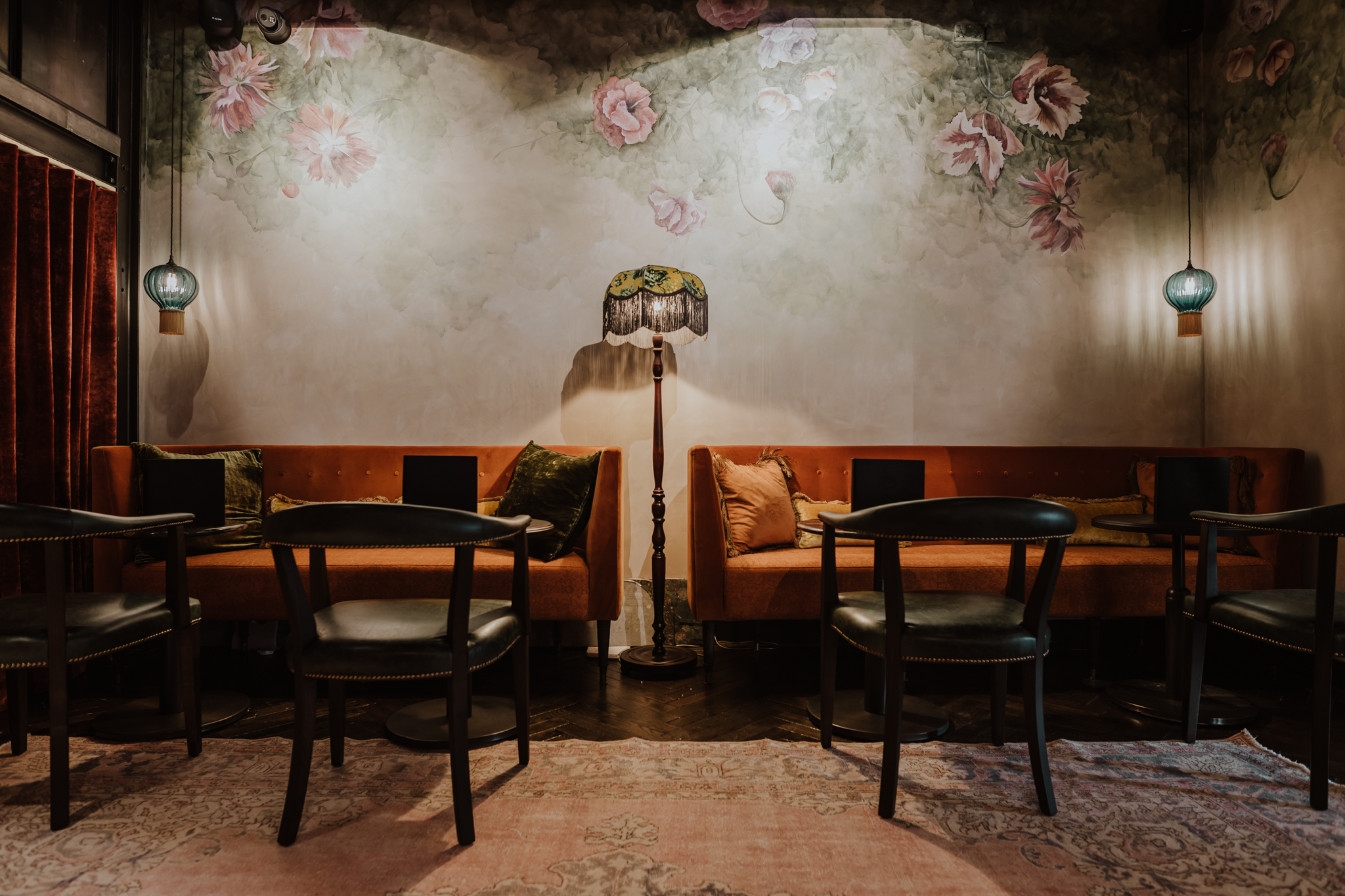 Cozy meeting space in The Gun London with plush seating and floral mural for networking events.