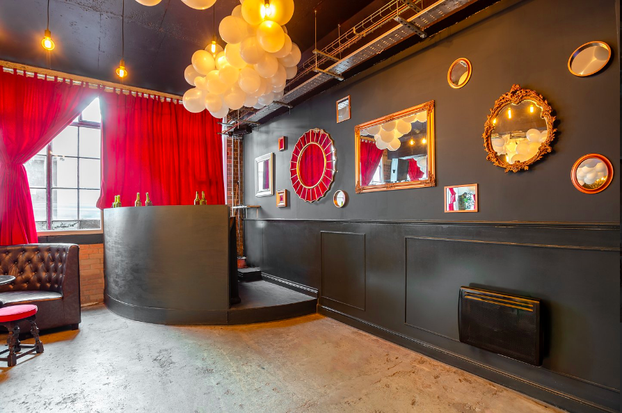 Stylish U7 Lounge venue with black wall, mirrors, and red curtains for events.