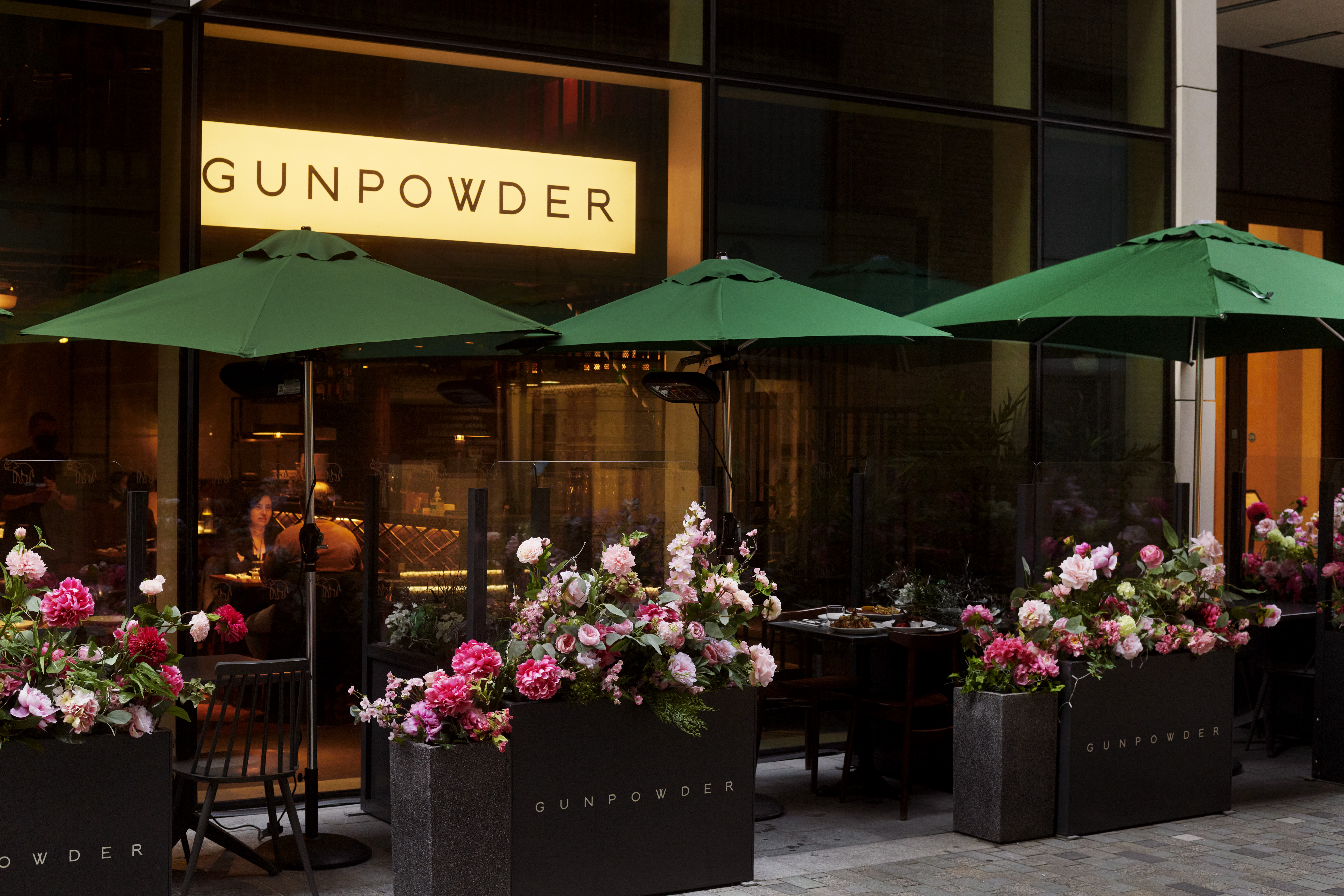Outdoor dining at Gunpowder Tower Bridge with green umbrellas, perfect for events.