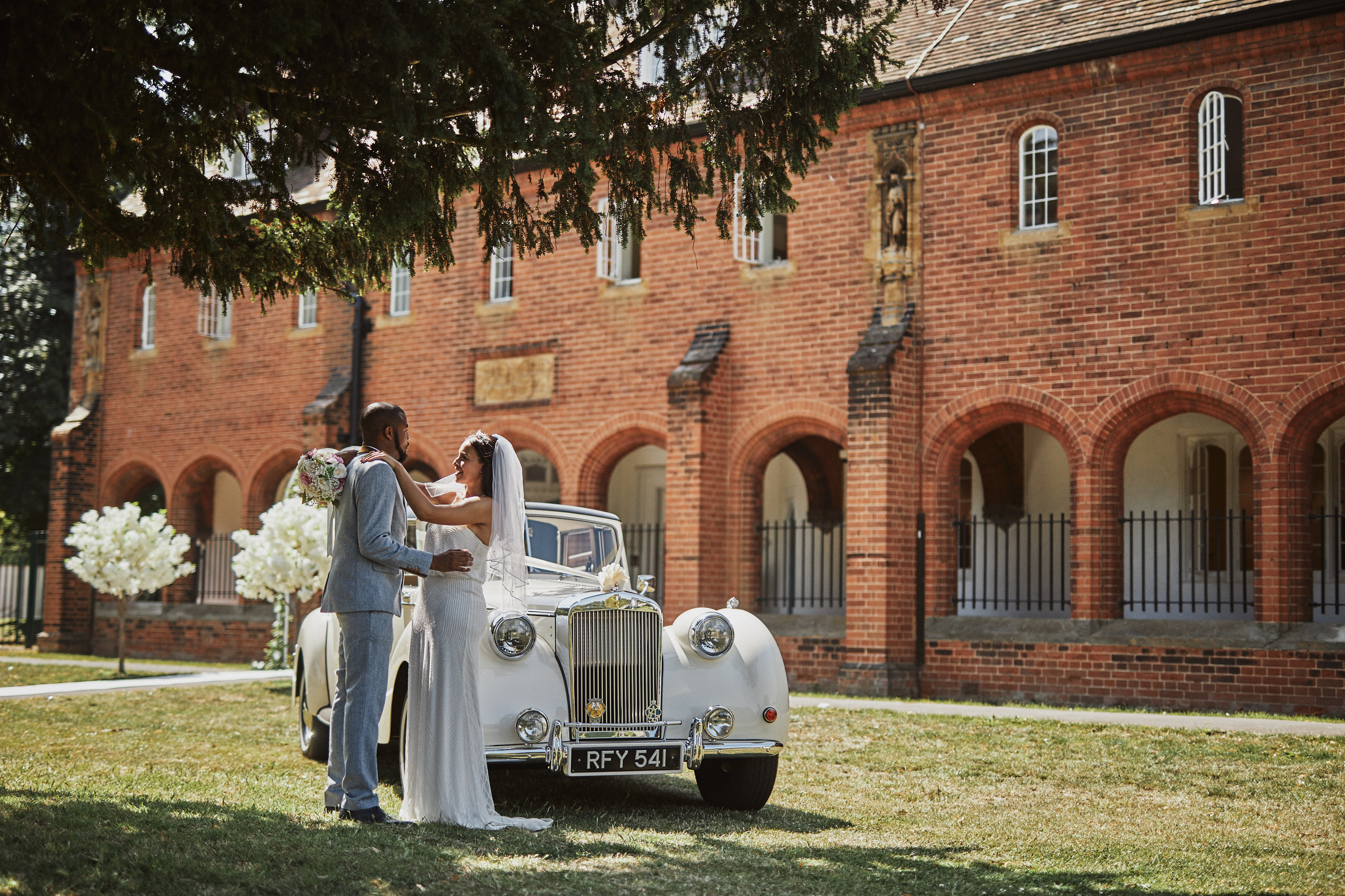 Byculla Suite wedding scene with couple, vintage car, and lush greenery in Croydon.