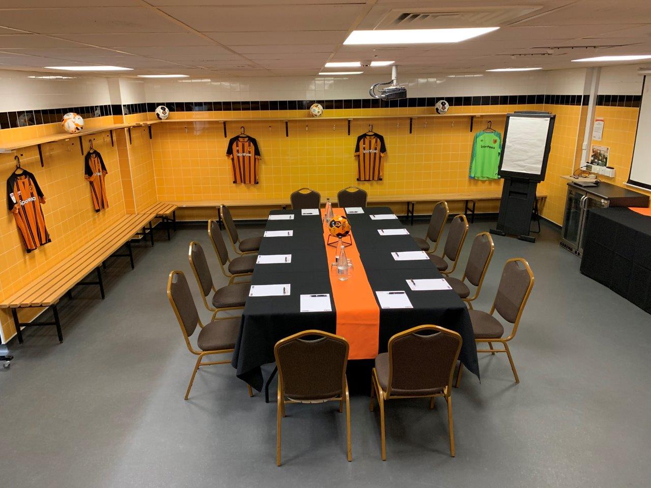 MKM Stadium locker room meeting space with orange tablecloth for team-building events.