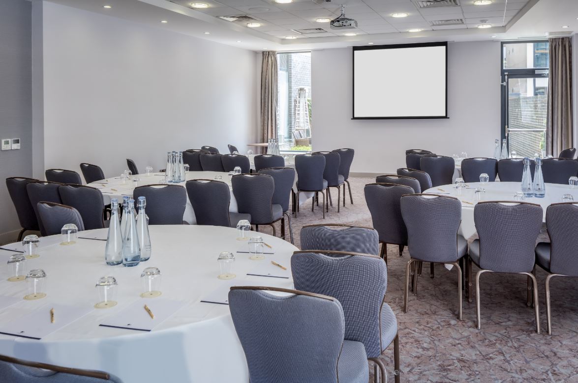 Kings Cross Suite meeting room with round tables, ideal for corporate events and conferences.