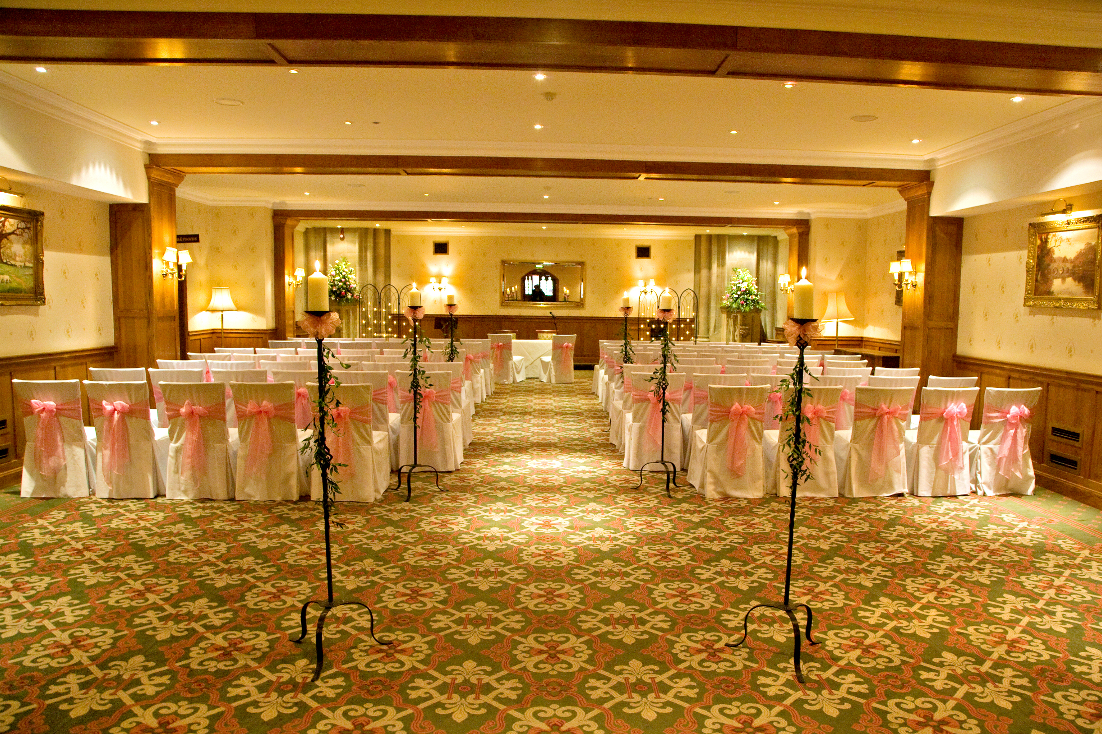 Harry Clarke in elegant wedding venue with pink-sashed chairs at Ashdown Park Hotel.