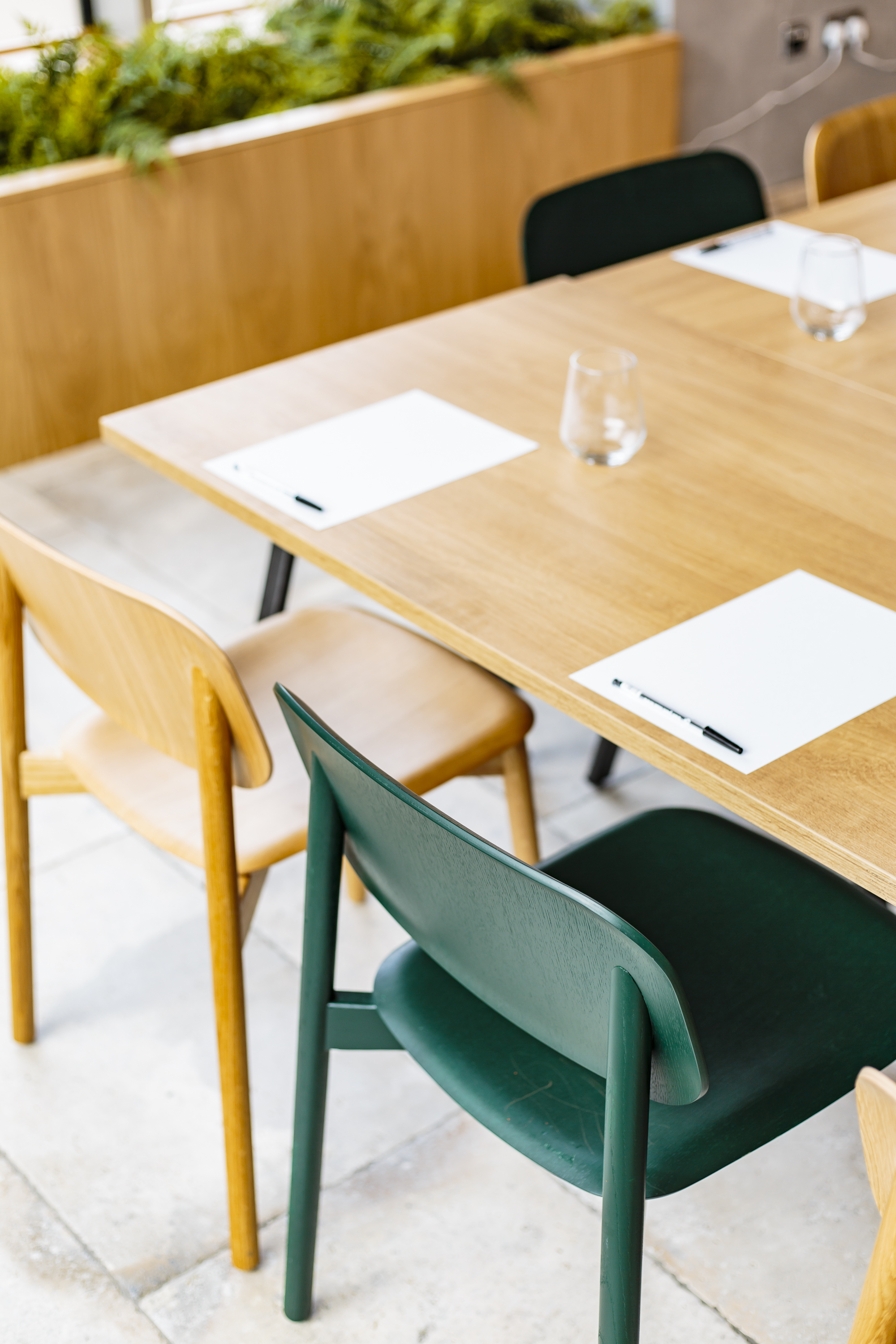 Minimalist meeting space in FoodWell with wooden chairs, notepads, and pens for collaboration.