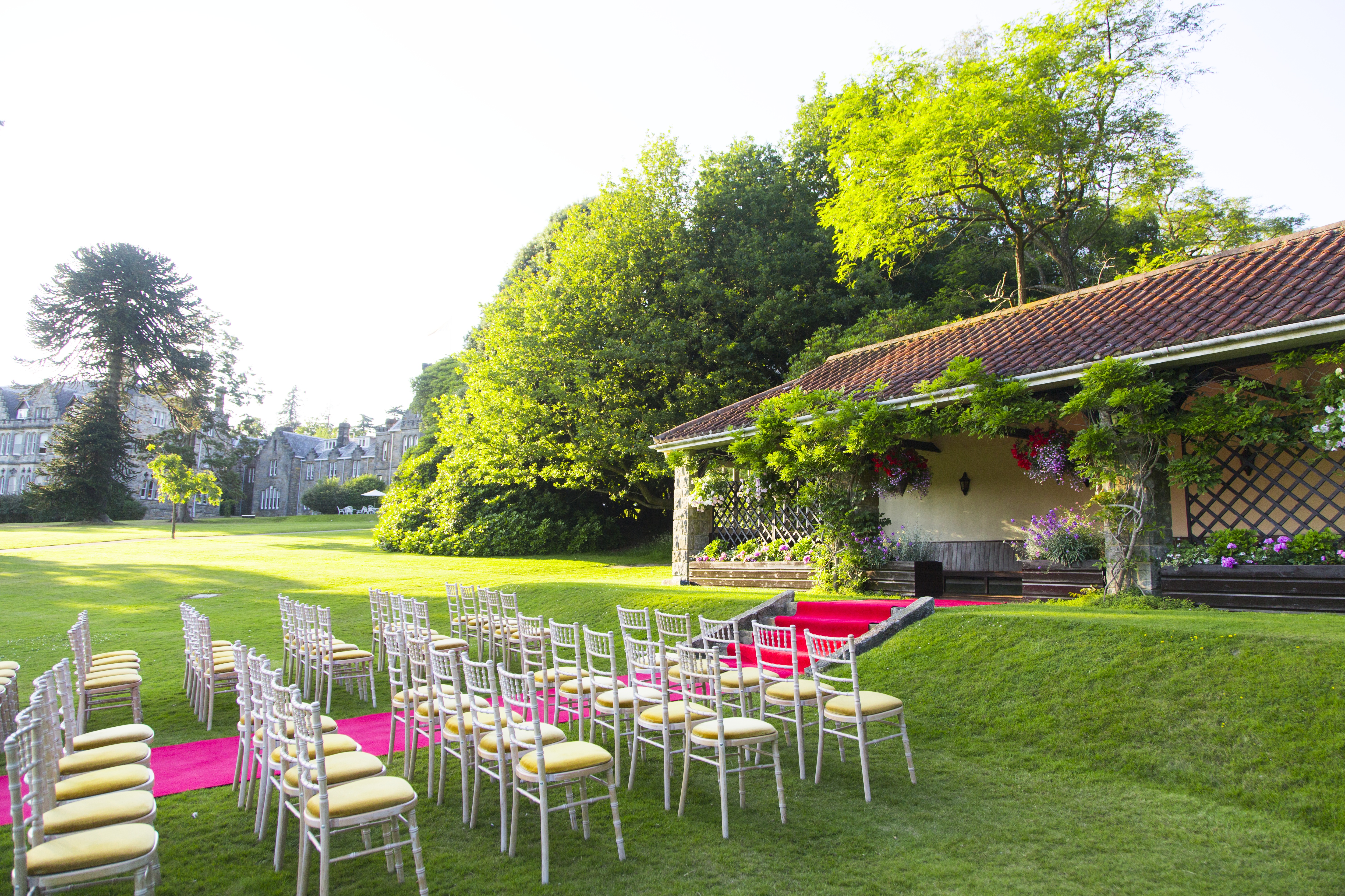 Outdoor wedding venue at Ashdown Park with elegant chairs on pink carpet.