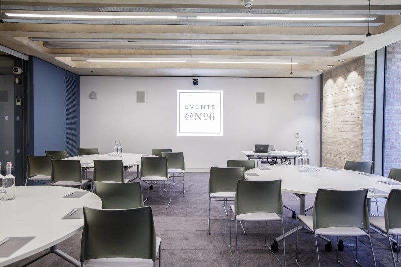 Modern meeting room with round tables, ideal for workshops and corporate events.