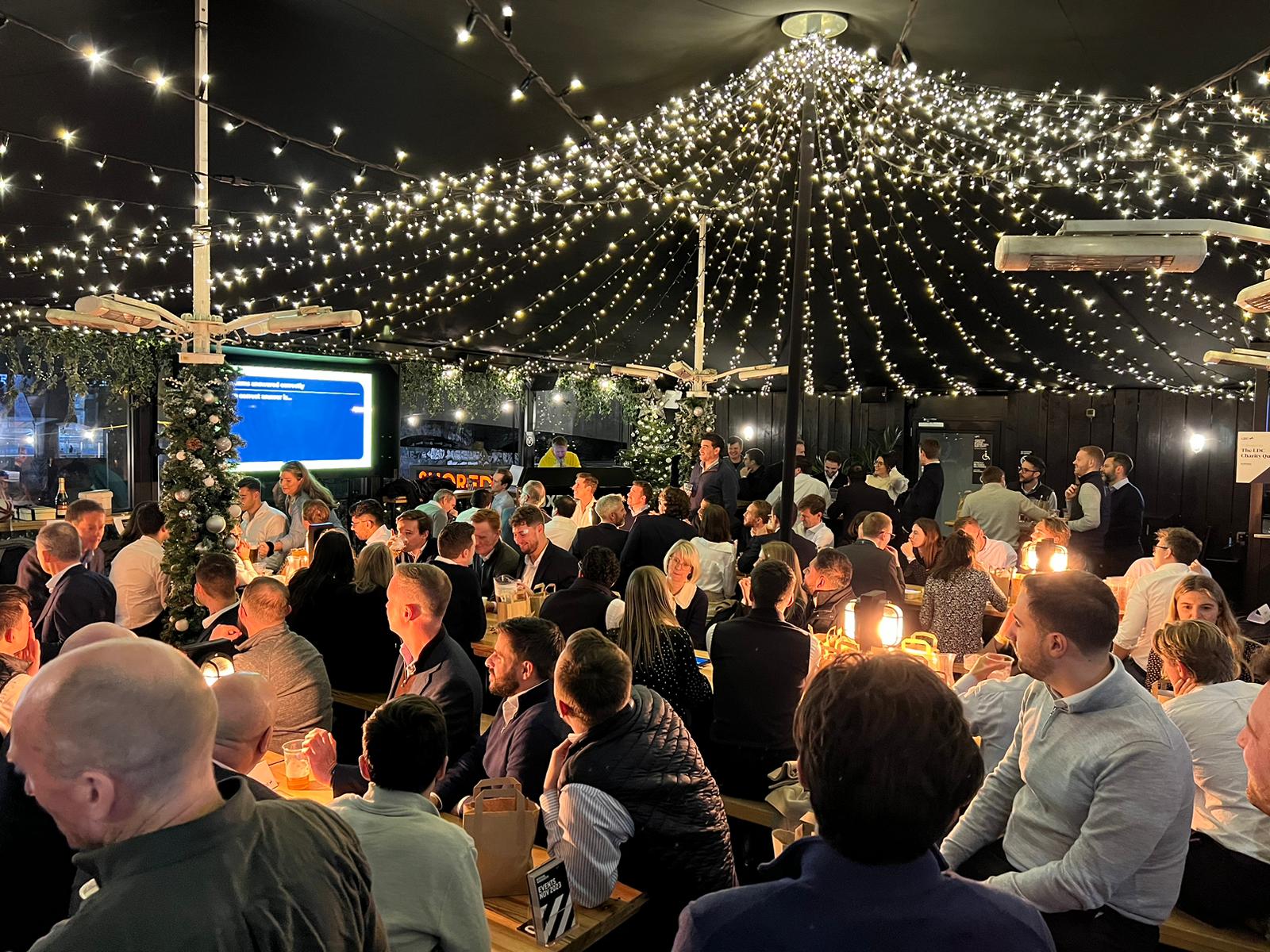 Vibrant networking event at Boxpark Shoreditch under twinkling lights.