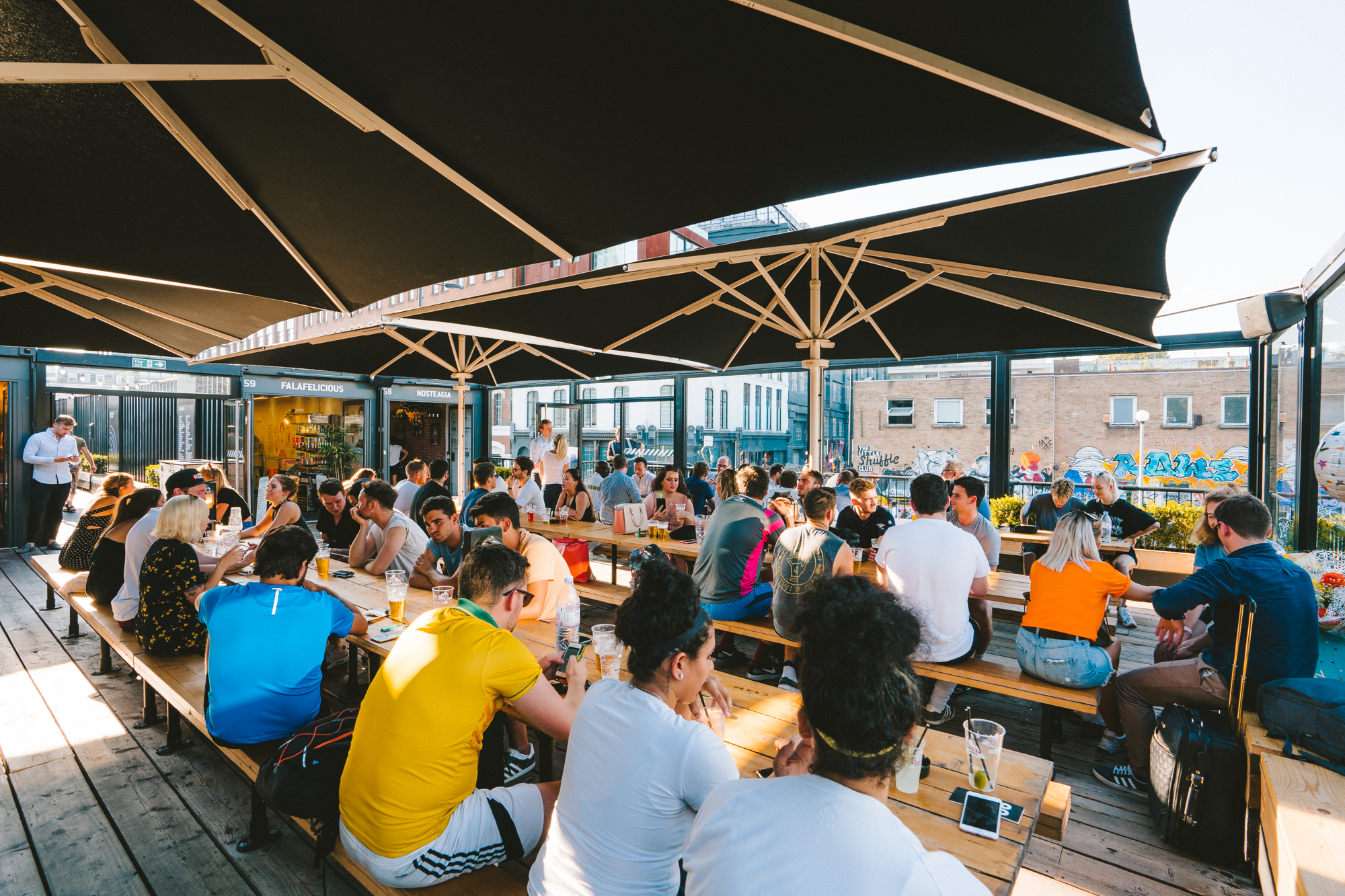Vibrant outdoor event at Boxpark Shoreditch with communal tables for networking.