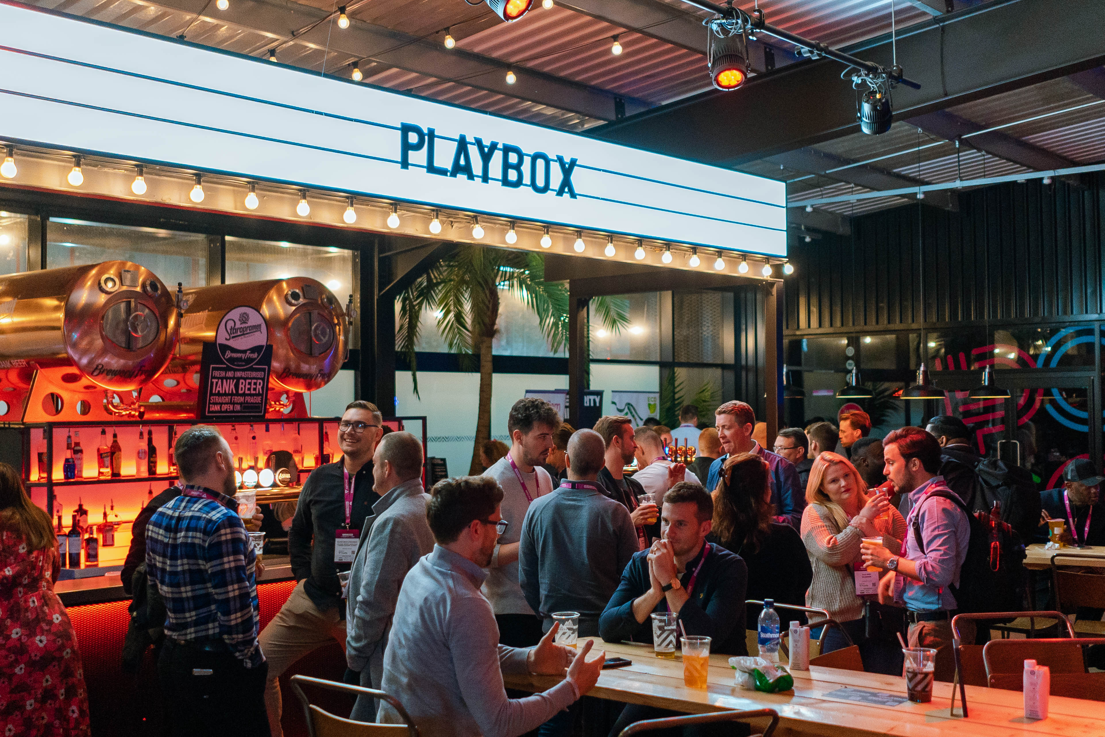 Vibrant networking event at PlayBox Bar, Boxpark Wembley with modern decor and warm lighting.