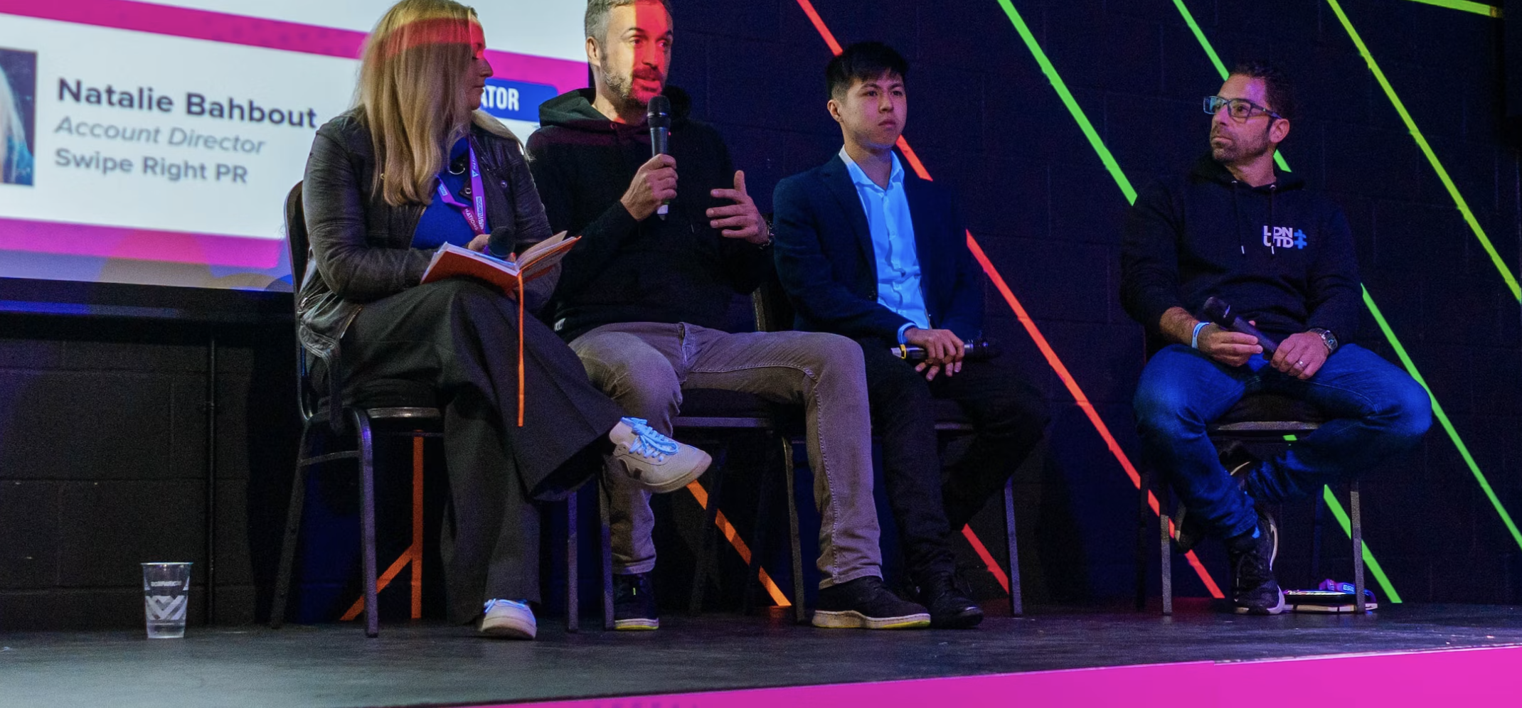 Panel discussion at Playbox Room, Boxpark Wembley, featuring diverse speakers and vibrant decor.