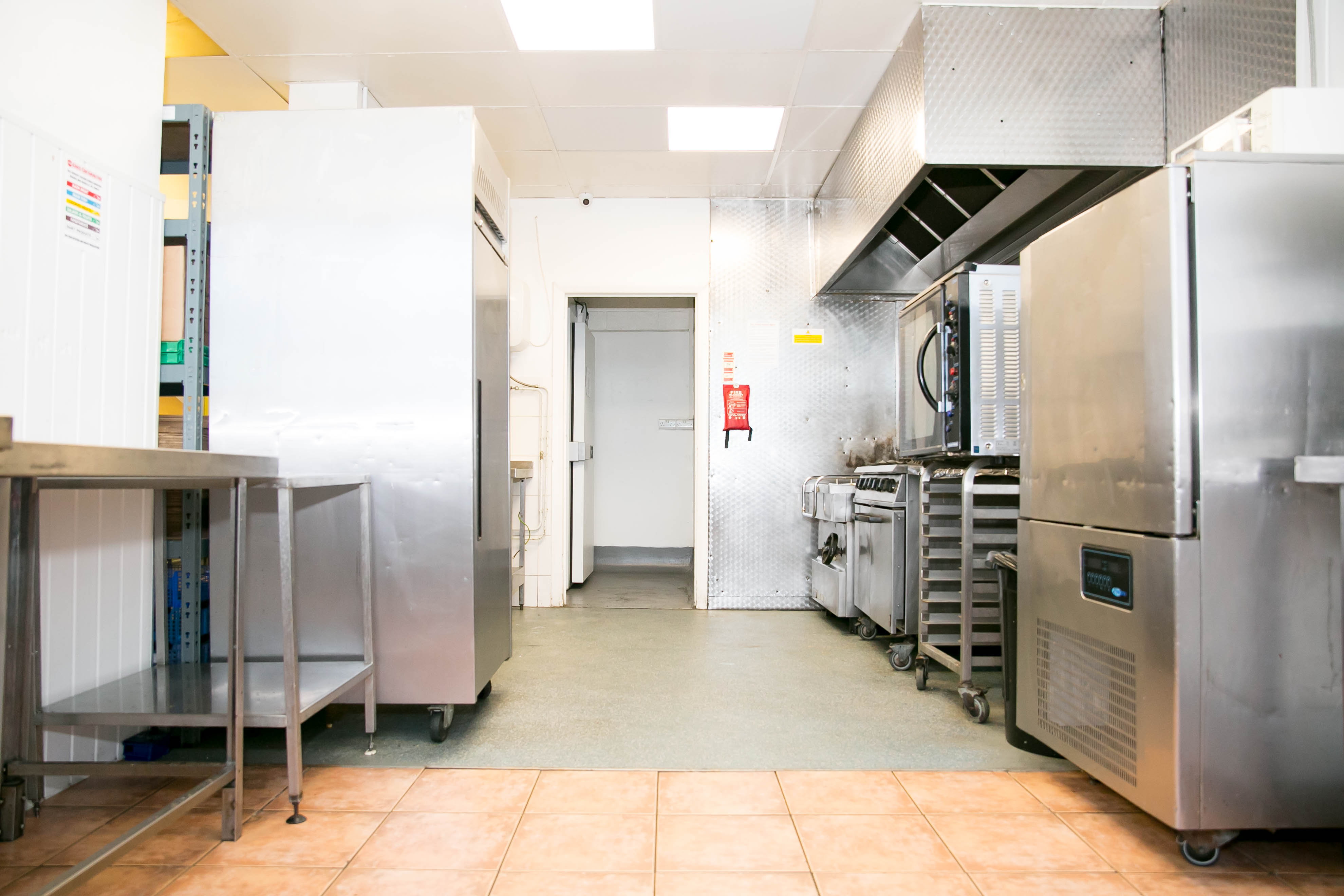 Commercial kitchen at The Olive Grows Ltd, featuring stainless steel appliances for catering events.