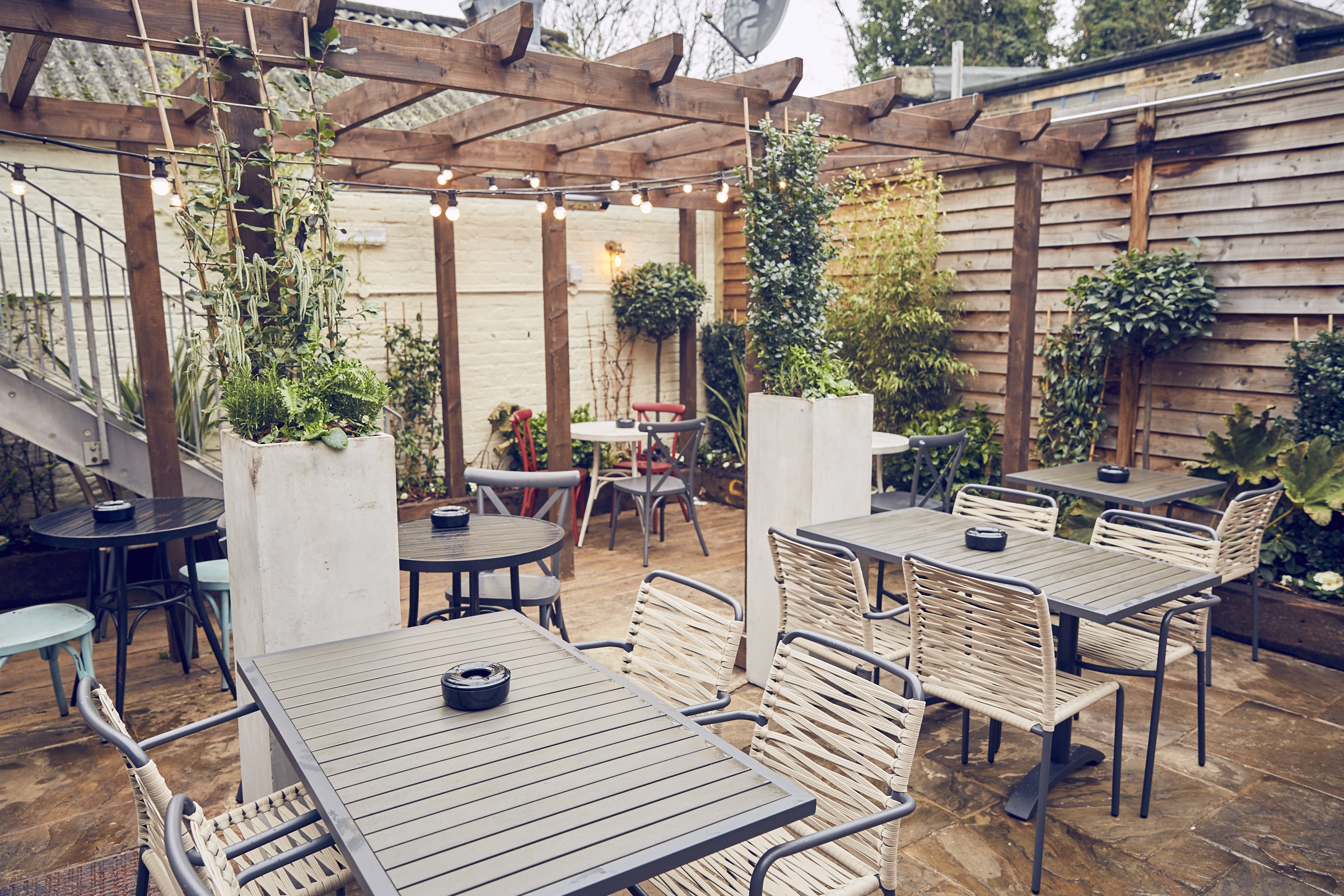 Charming outdoor event space with wooden pergola for networking and celebrations.