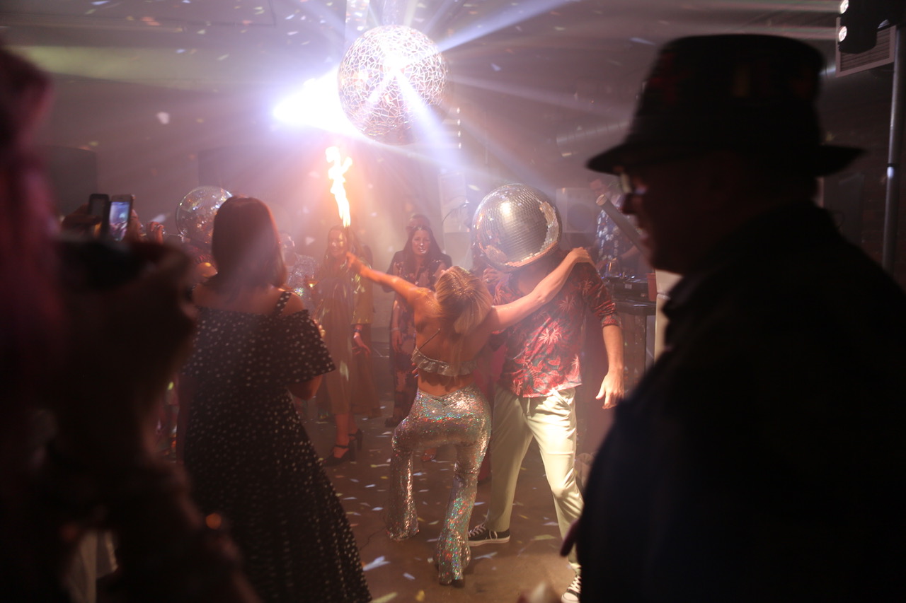 Vibrant dance floor with disco lights at Loft Studios event with fire performers.
