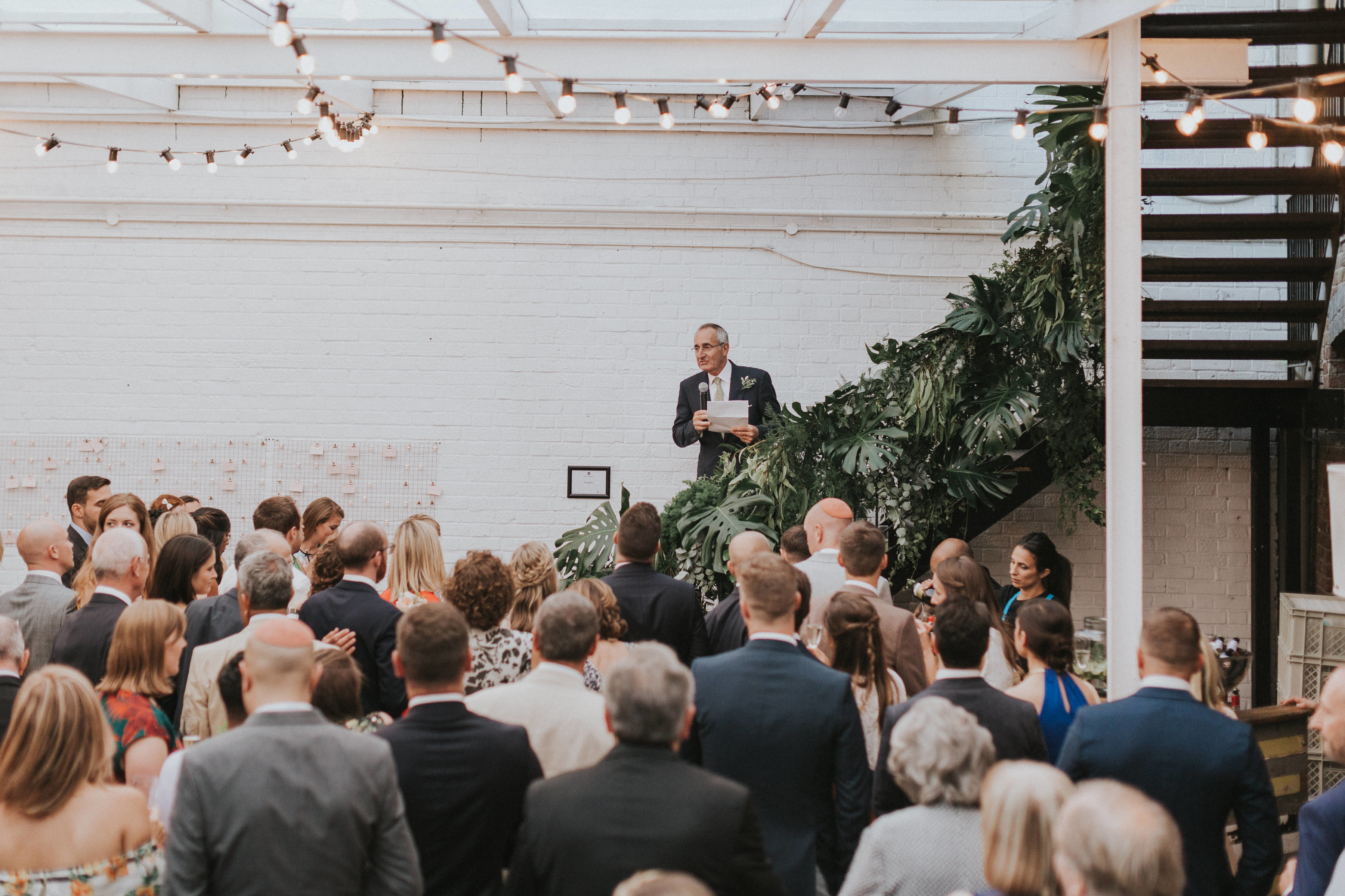 "Daylight Courtyard event with speaker, string lights, networking atmosphere"