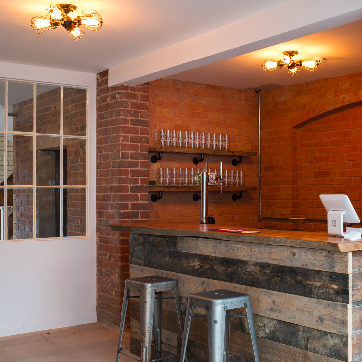 Stylish rustic bar with wooden counter, ideal for networking events and cocktail receptions.
