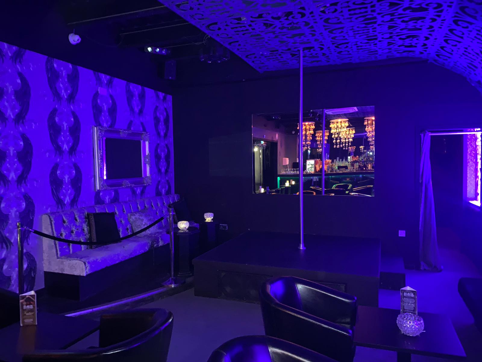 Stylish Black Diamond Gentleman's Club event space with purple accents and central pole.