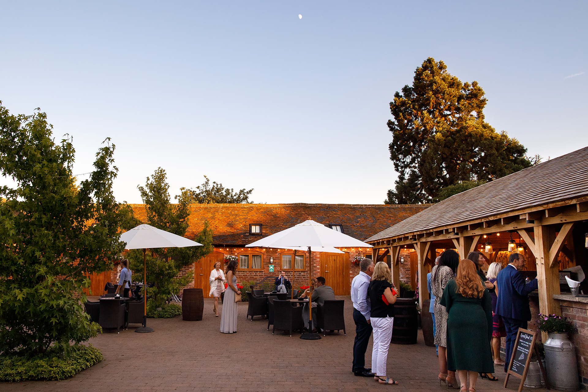 Outdoor event space at Mythe Barn with rustic charm and stylish umbrellas for gatherings.