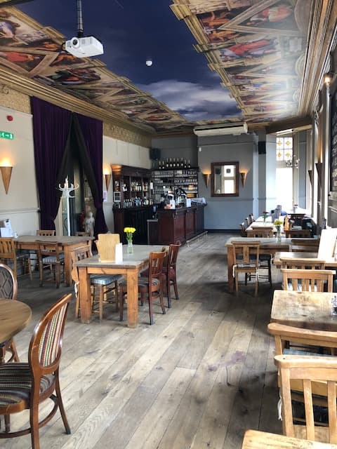 Spacious function room in The Angelic with rustic tables, ideal for events and workshops.
