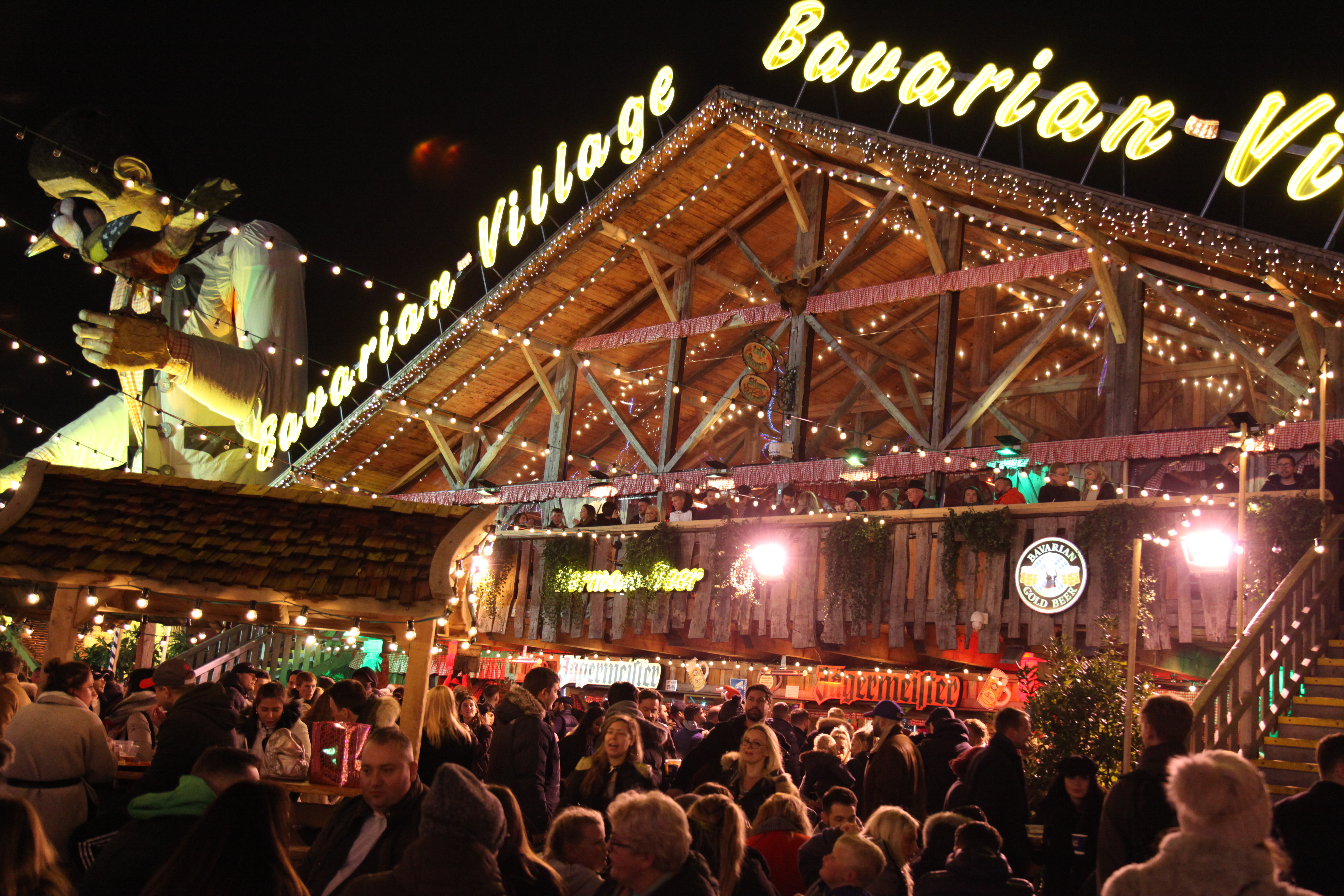Vibrant outdoor event at Cafe Bavaria with rustic architecture and twinkling lights.