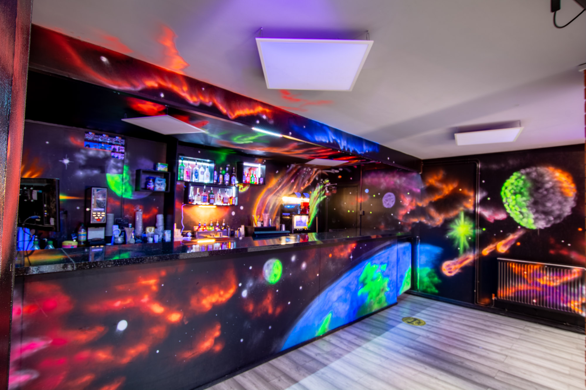 Vibrant space-themed bar with colorful murals for social events and themed parties.