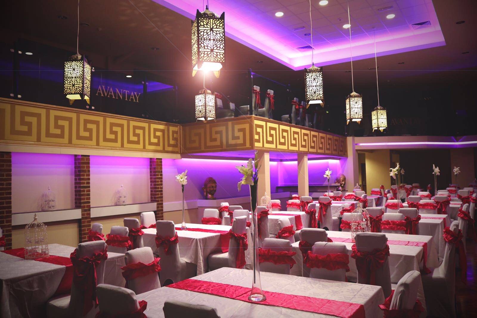 Elegant banqueting suite with white tables and red accents for corporate events or weddings.