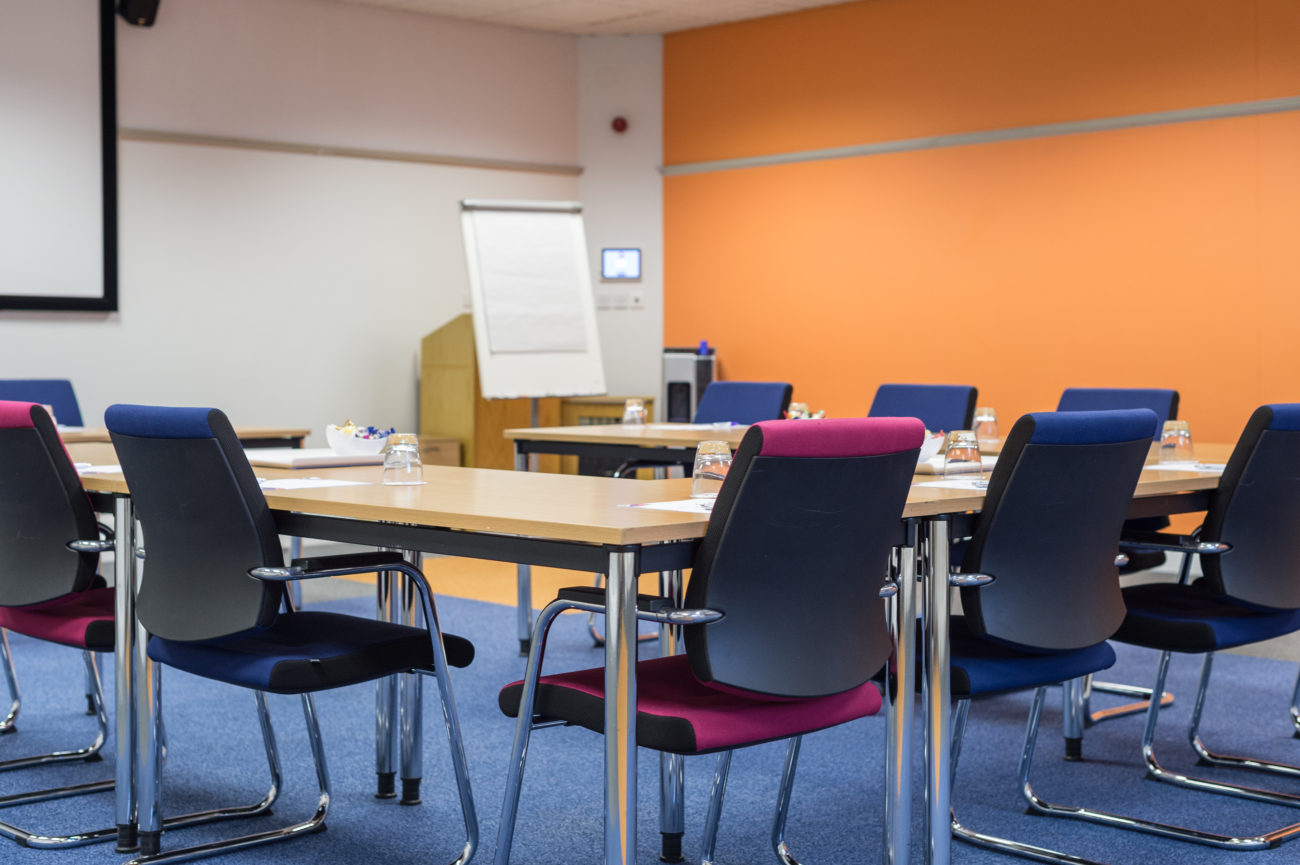 Medium training room with U-shaped table, colorful chairs for collaborative meetings.