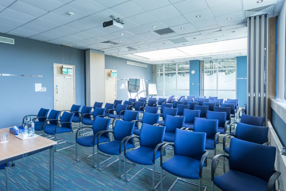 Meeting room with blue chairs, projector, and whiteboards for workshops in Holywell Park.