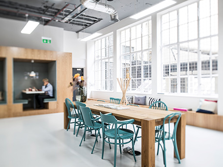 Modern meeting room with wooden table and teal chairs, ideal for collaborative events.