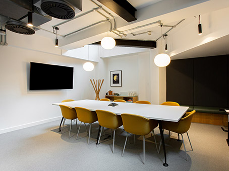 Modern meeting room with white table and yellow chairs for collaborative sessions.