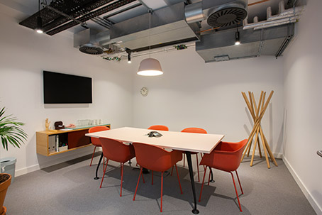 Modern meeting room with orange chairs, ideal for collaborative brainstorming sessions.