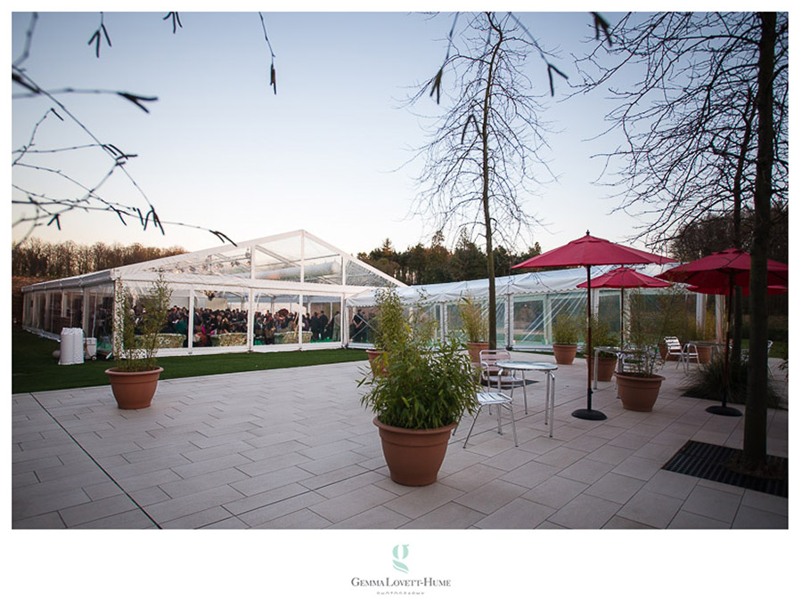 Stylish outdoor event space with clear marquee and red umbrellas at Alnwick Garden.