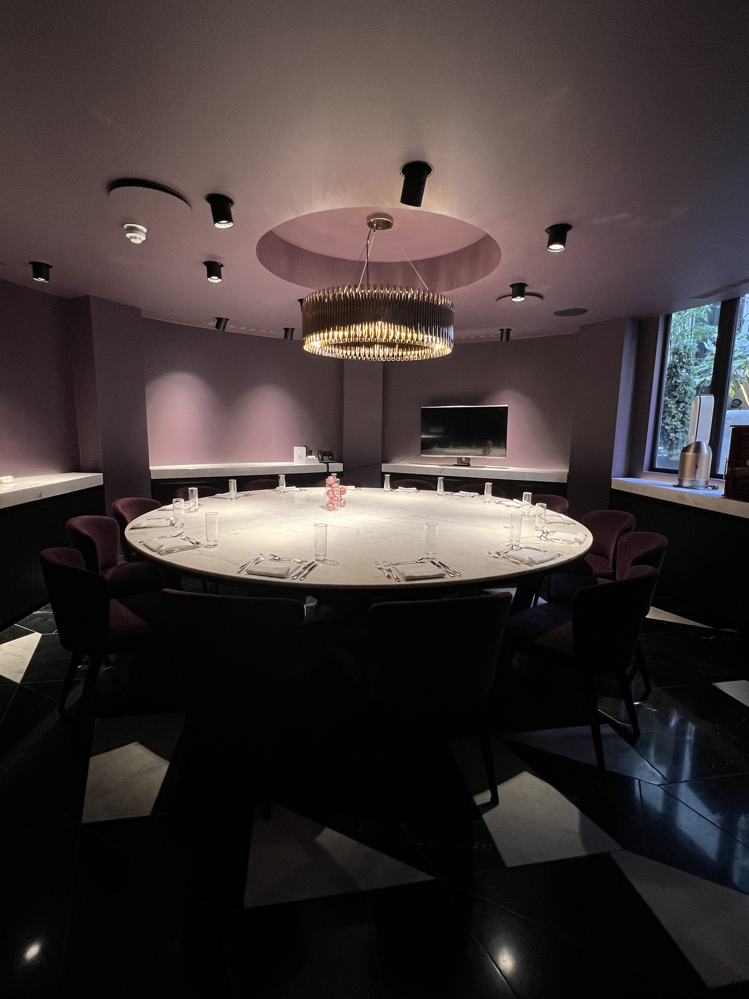 Sophisticated meeting room with round table and chandelier for corporate events.