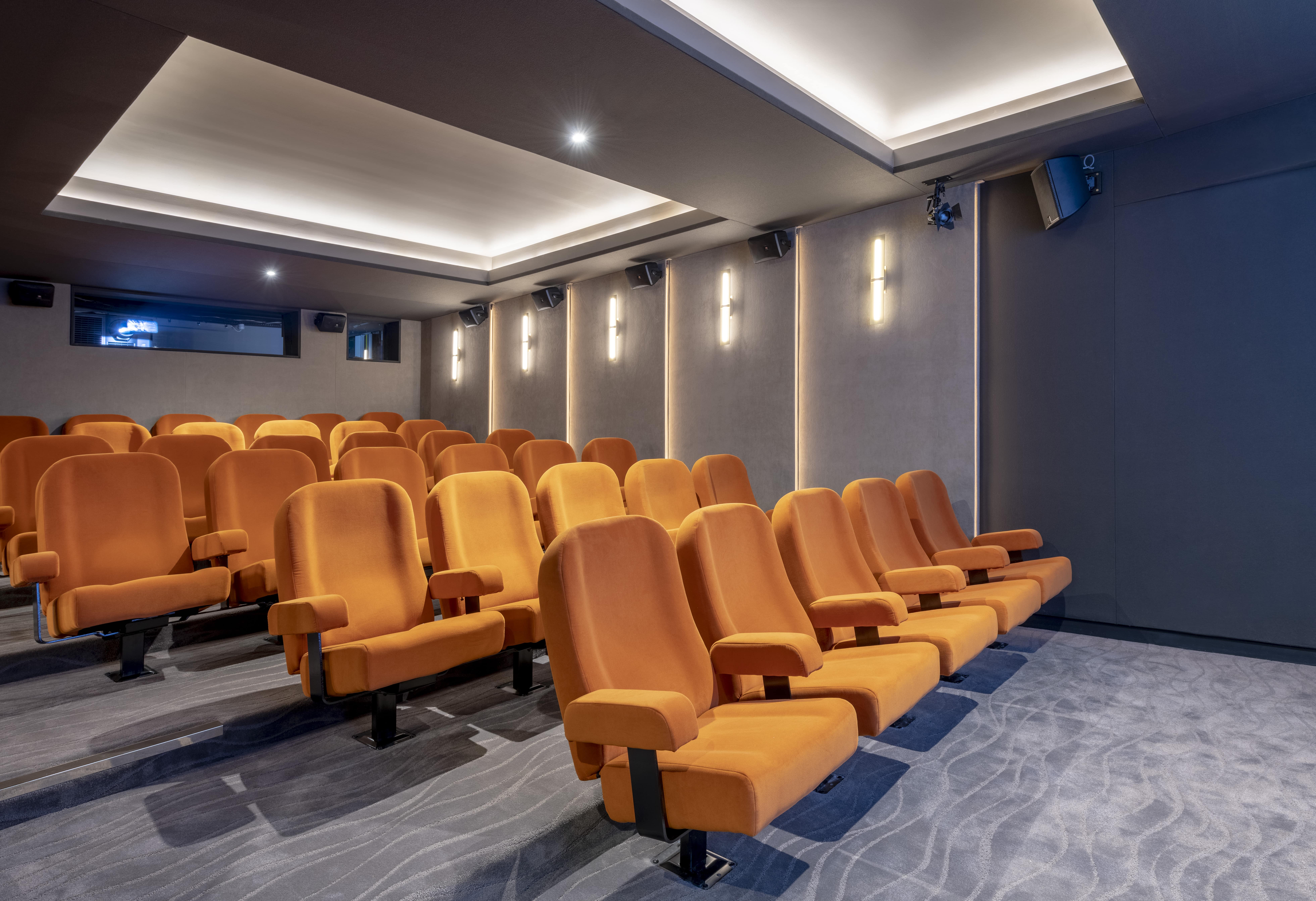 Ciné Lumière 2 theater with plush orange seating for film screenings and corporate events.