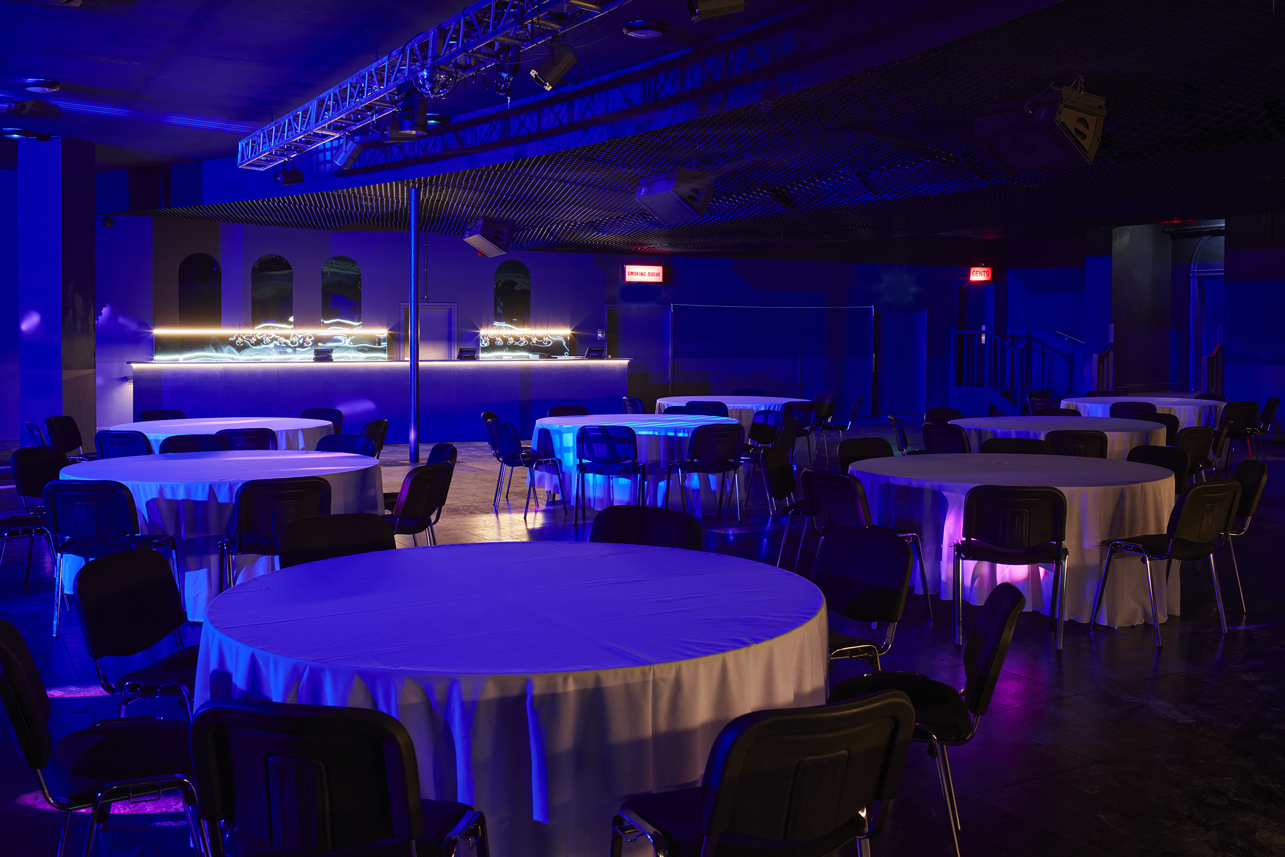 Concert Hall in EartH set for a corporate meeting with round tables and blue lighting.