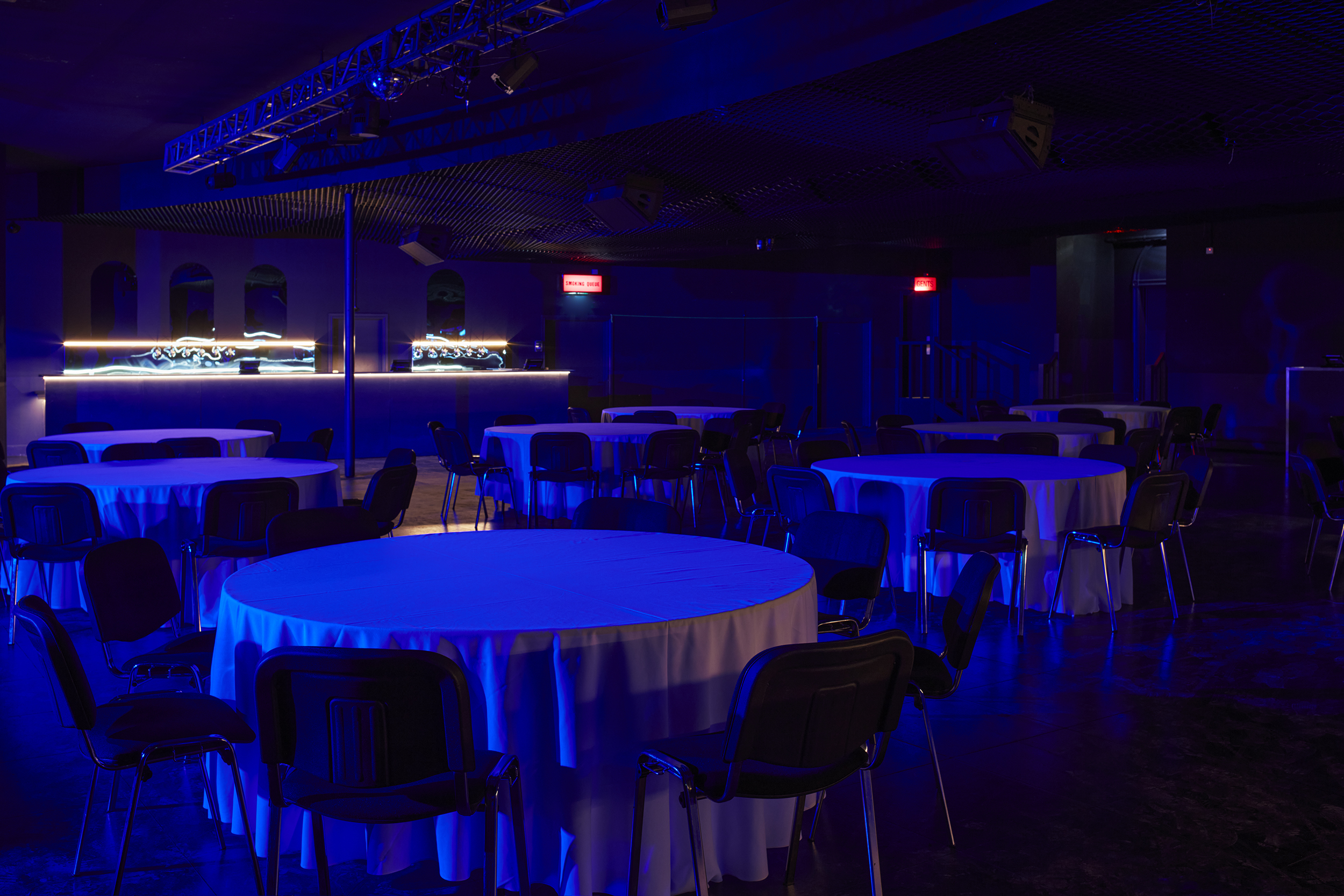 Versatile Concert Hall event space with round tables and ambient blue lighting.