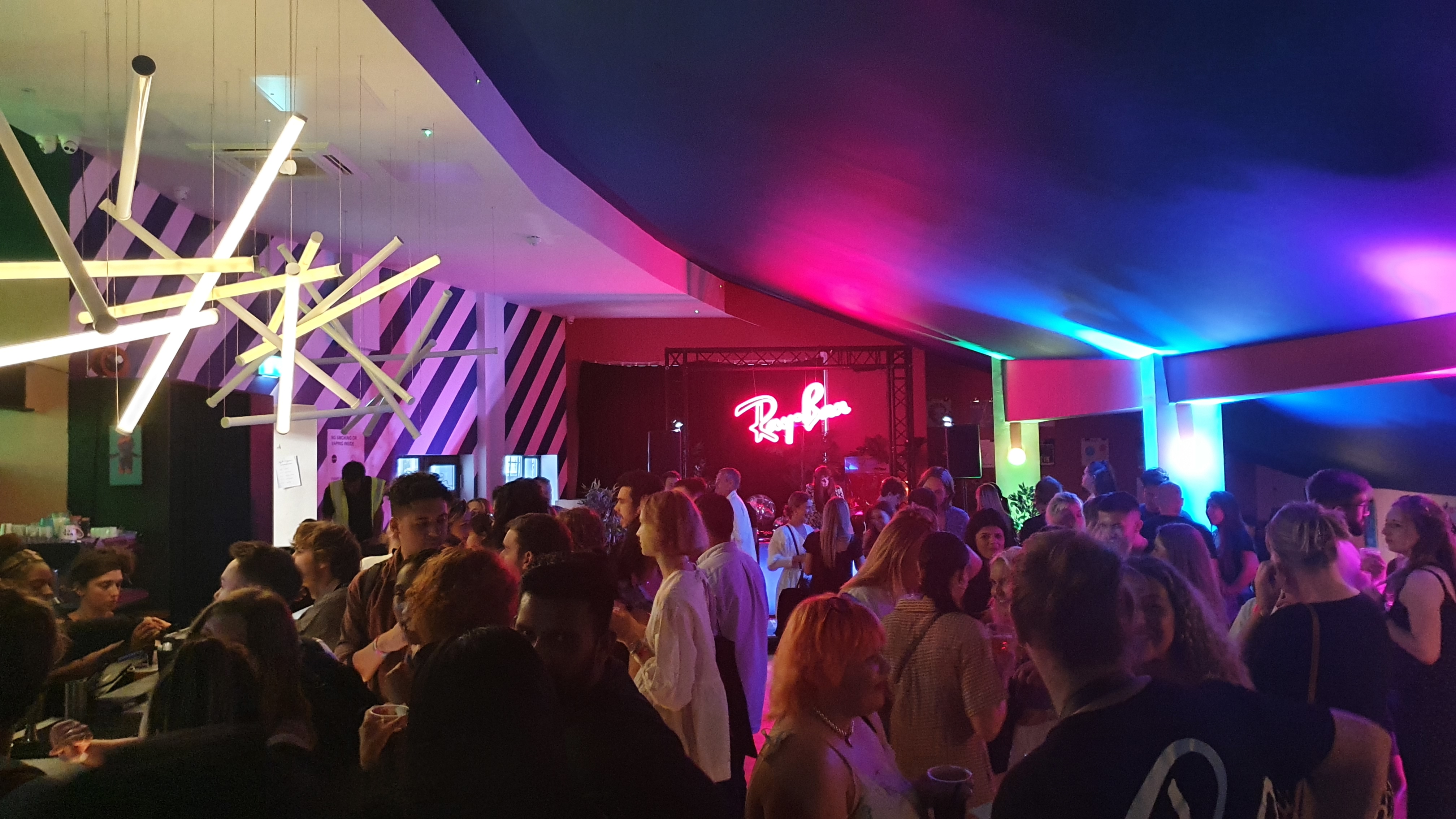 Vibrant Bar + Kitchen event space with colorful lighting for networking and performances.