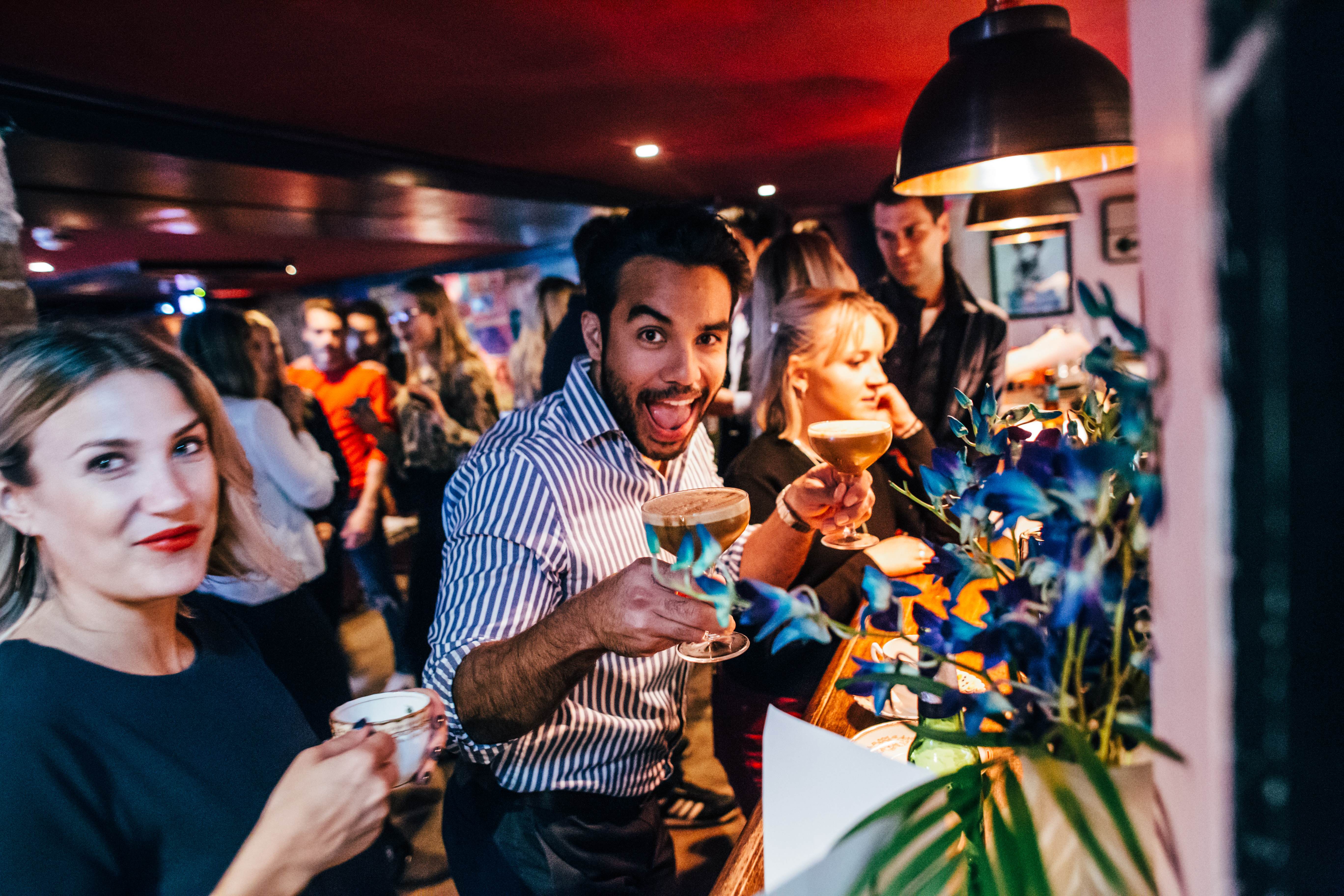 Vibrant social event at Flatmates Den, lively bar with cocktails and networking.