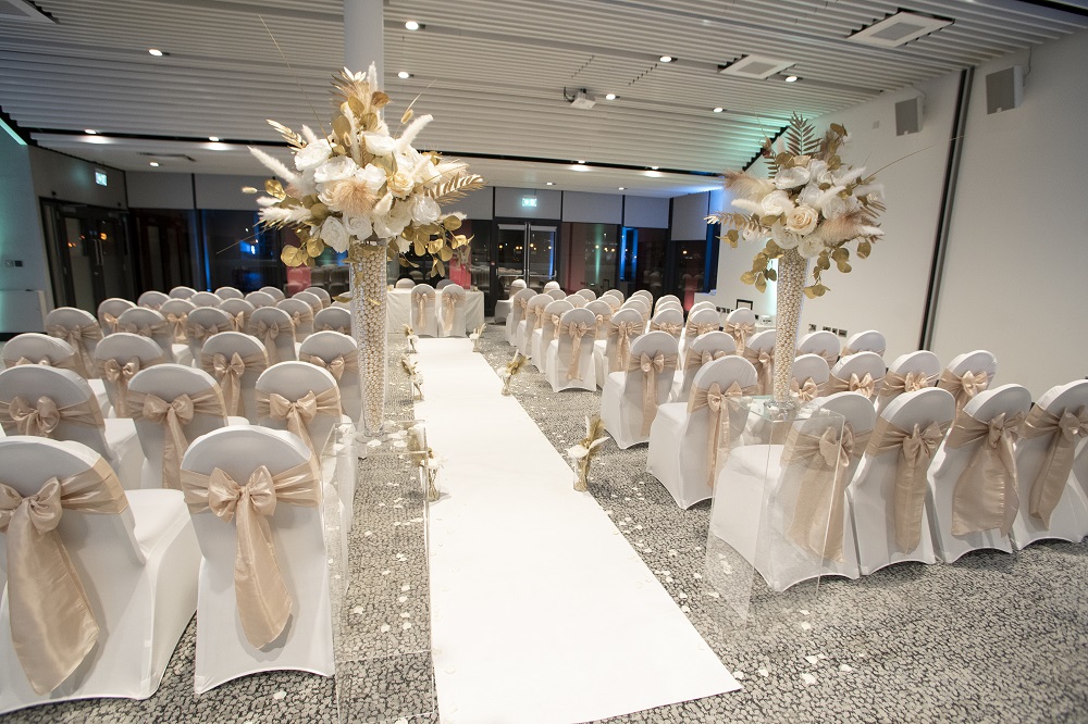 Elegant wedding ceremony setup at Pier Eight Room, featuring white chairs and floral decor.